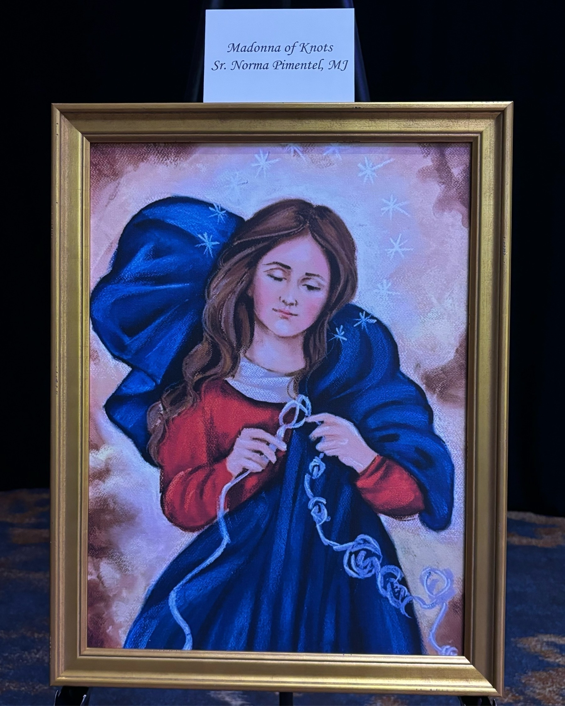 A painting entitled Madonna of Knots, depicting Mary, Mother of God, straightening out a rope. The artist is Sr. Norma Pimentel, MJ.