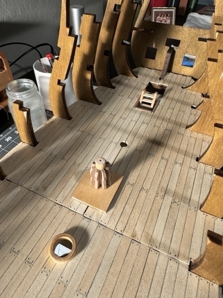 Close up view of the lower deck of Flying Dutchman model ship showing a ladder to the lower hold and a capstan. 