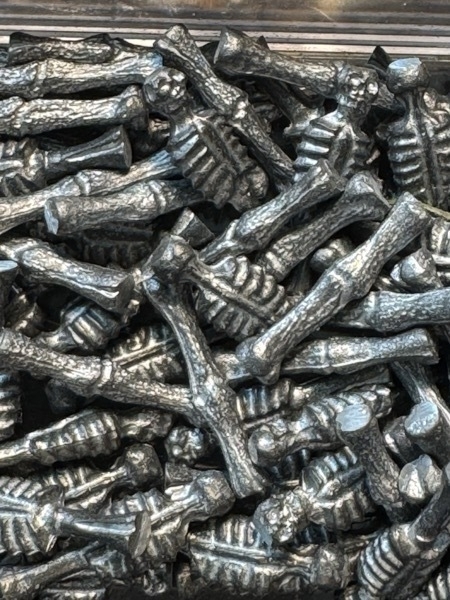 Close up shot of bones and skeletal torsos made of cast metal that are used as the spindles holding up the railings on the captains cabin. 