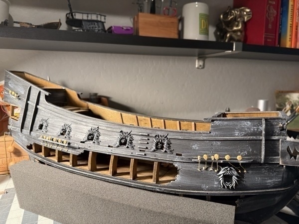 View of the starboard side of the flying dutchman model ship showing all the cannons sticking out from the gun ports and all the rigging deadeyes in place along the hull. 