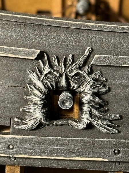 Close up view of one of the cannons on the flying dutchman model ship sticking out of the gunport on the outside of the hull. 