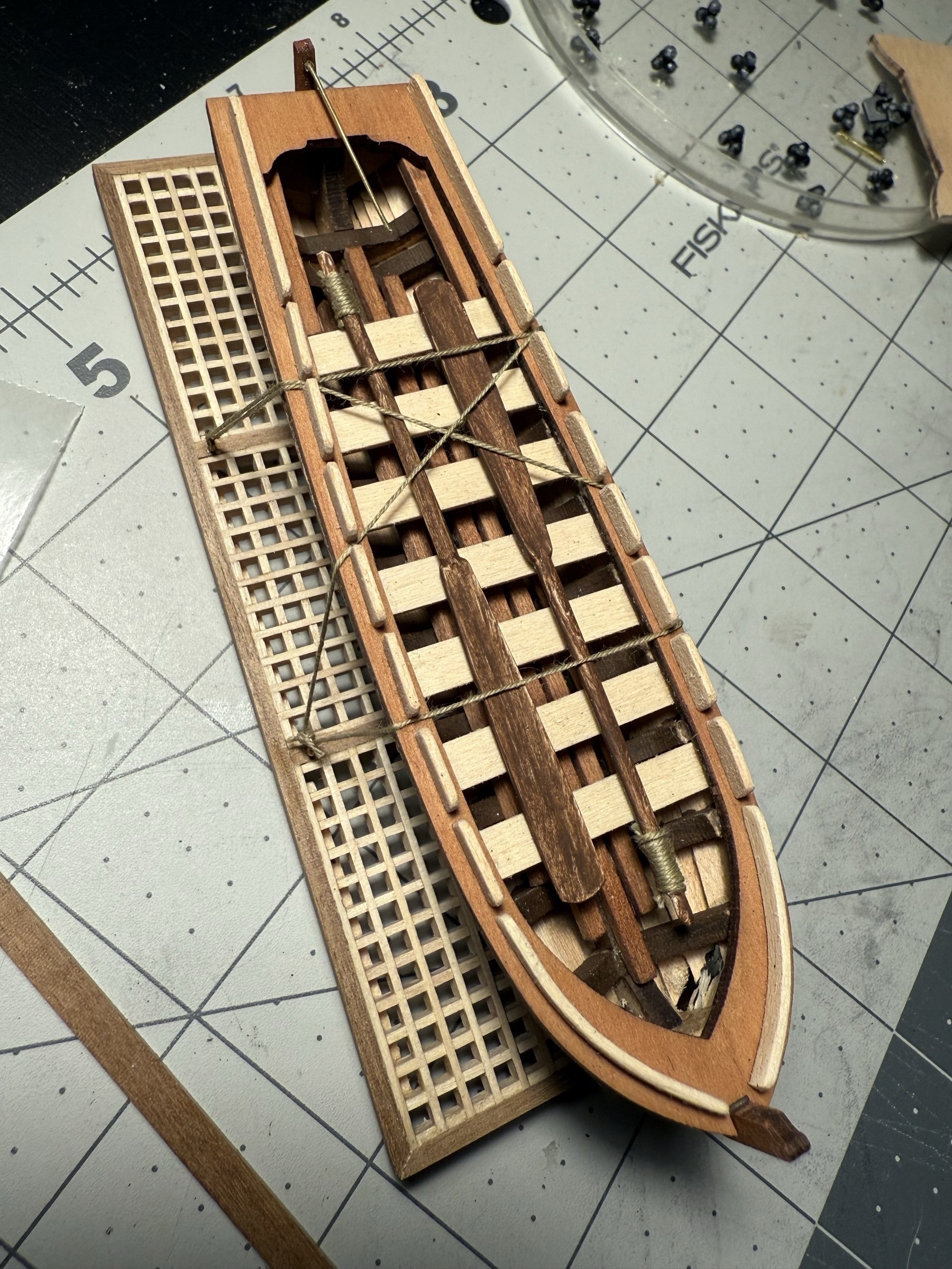 Overhead view of the skiff of the flying dutchman model ship. Shows the two oars I added along with it being tied down to the grating on which it will rest. 