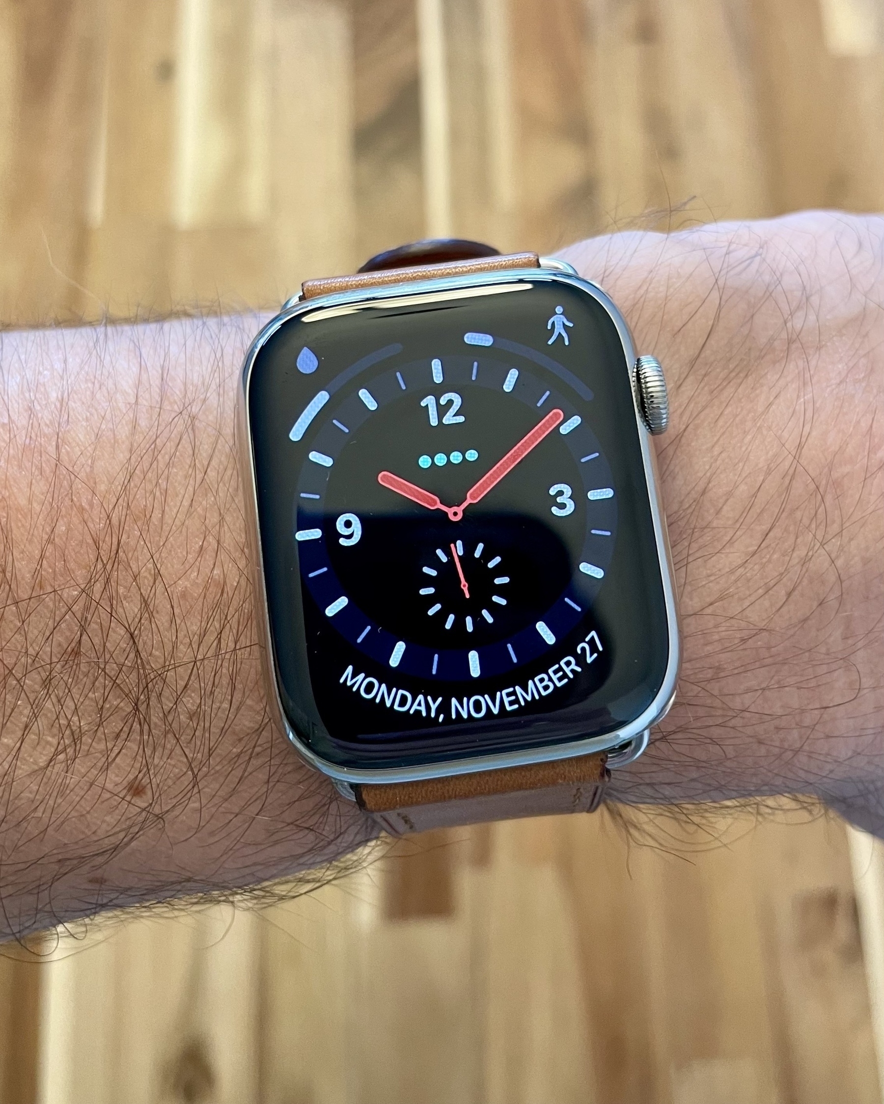An Apple Watch showing the Explorer face, with the upper-left complication showing water consumption and upper-right showing steps taken, both as progress bars. The bottom complication shows the day and date.
