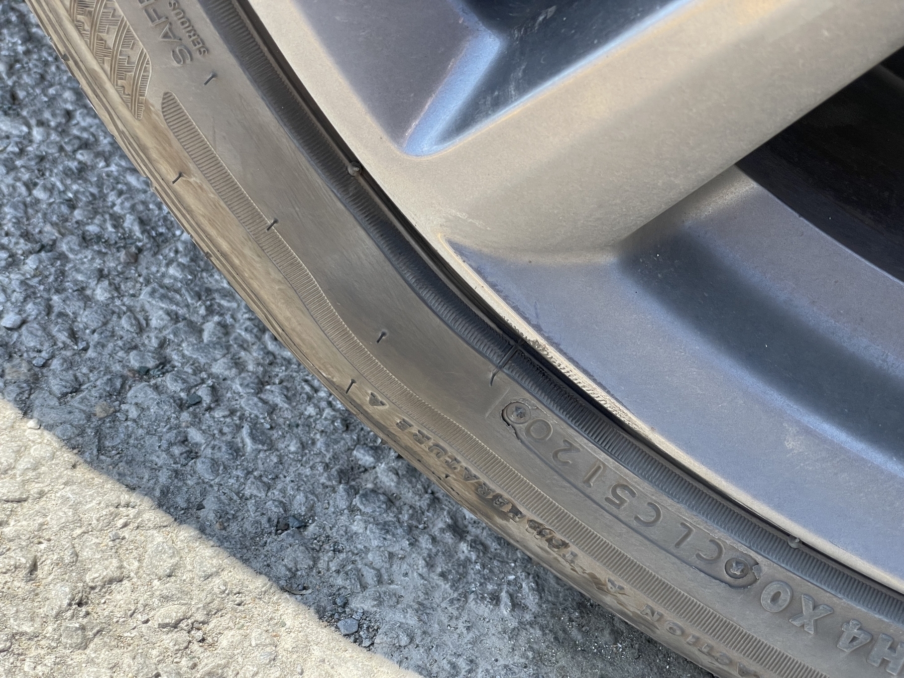 A close up photo of a low-profile tire clearly showing a bulge in the sidewall.