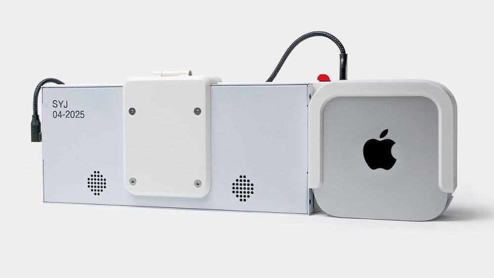A rectangular electronic device with speakers and a white panel is connected by a black cable to a small Apple device featuring the Apple logo.
Scott Yu-Jan's Portable M4 Mac mini