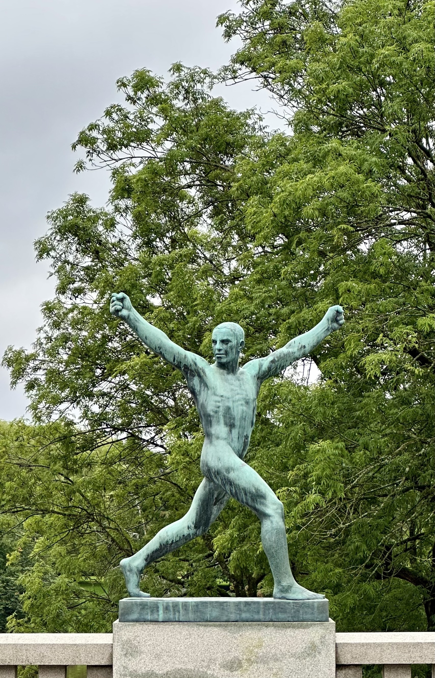 A nude statue of a man with his arms in the air stretching.