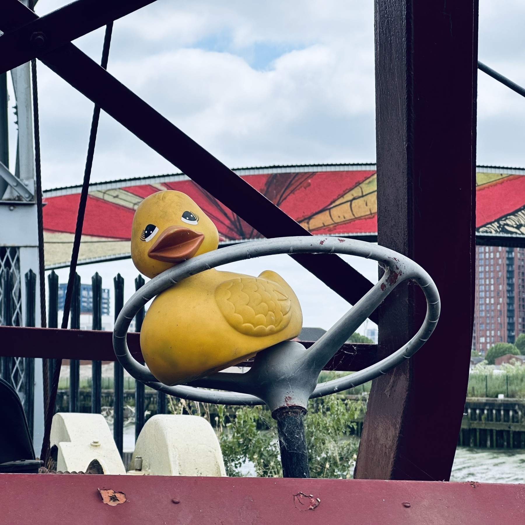 A yellow rubber duck wedged in to the steering wheel of an old crane.