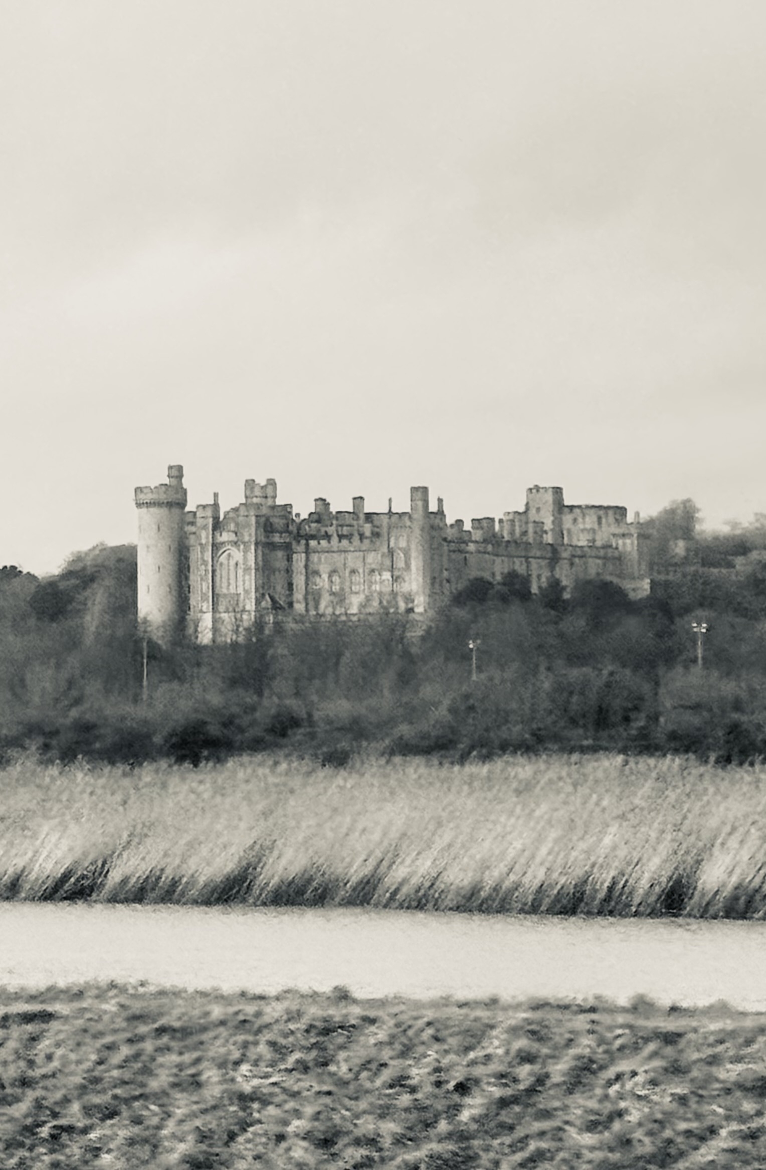 A slightly fuzzy black and white photo of Arundel castle taken from a train.