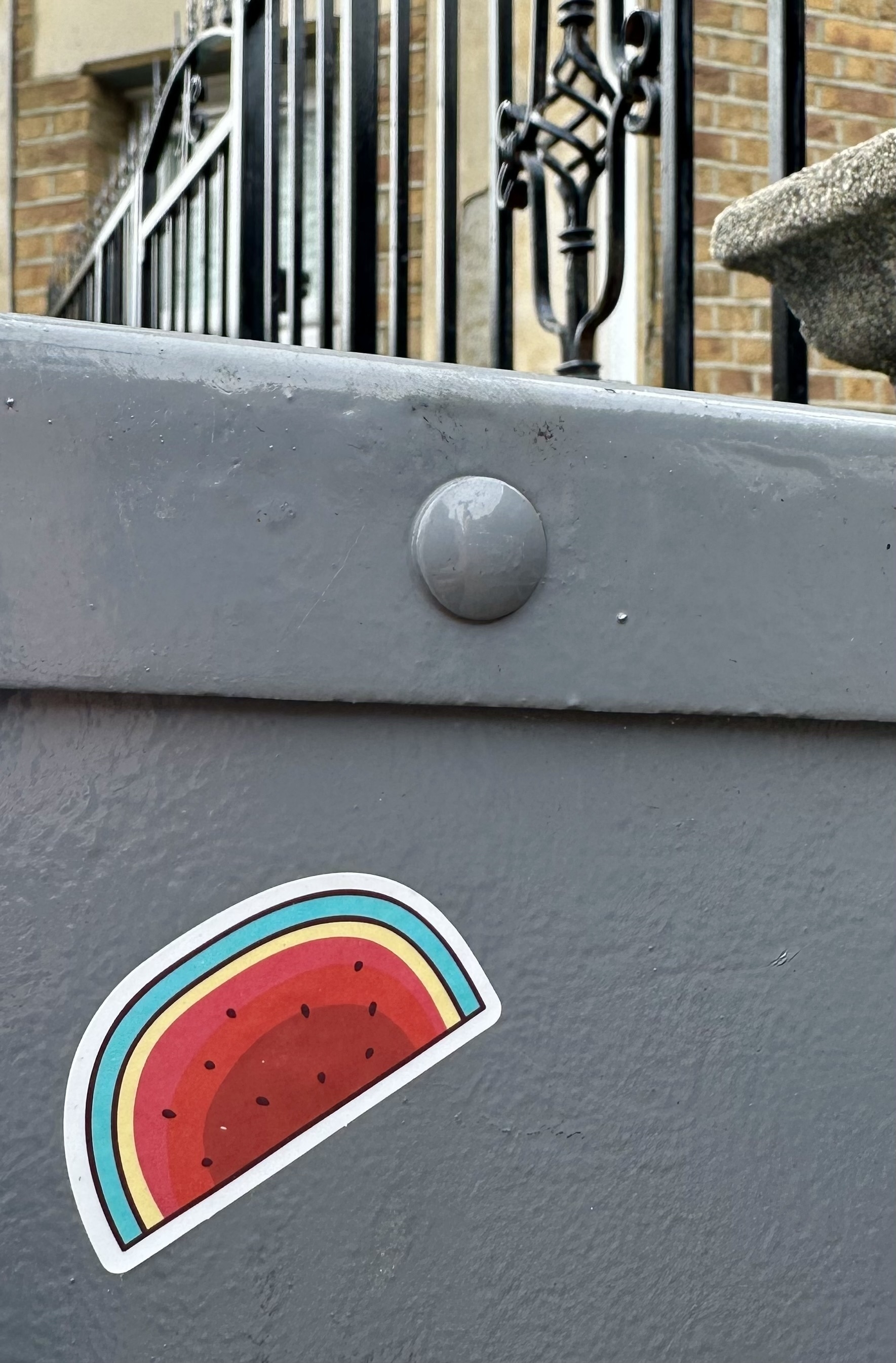 A sticker of a slice of watermelon on a piece of grey metal.