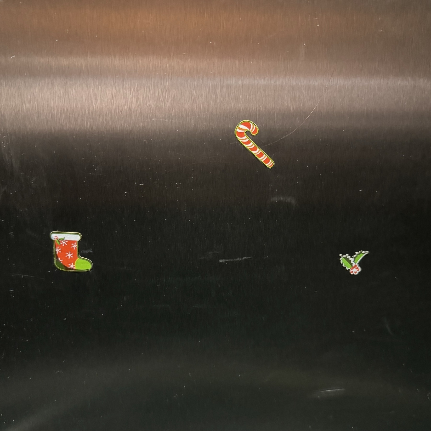 Xmas stickers of a stocking, candy cane and holly stuck on the wall of a lift.