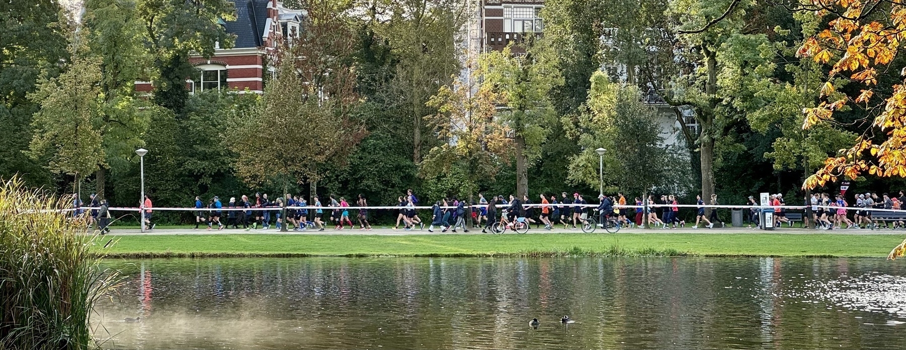 Runners from the Amsterdam Marathon passing a lake in Vondelpark.