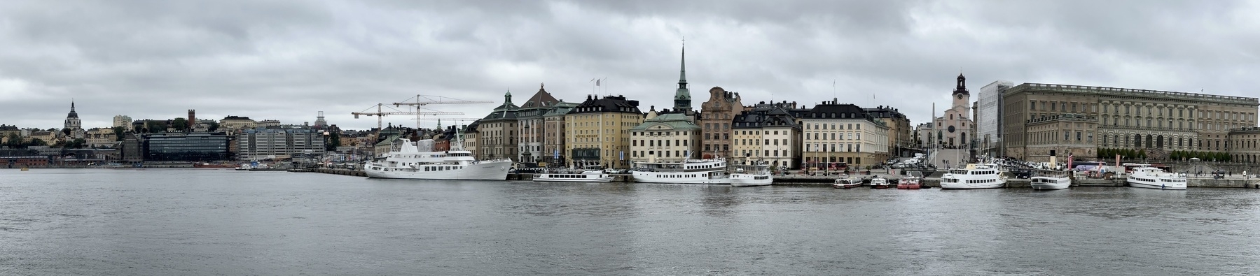A panoramic photo of Gamla Stan in Stockholm. Water and boats in the foreground, with the buildings of the island behind.