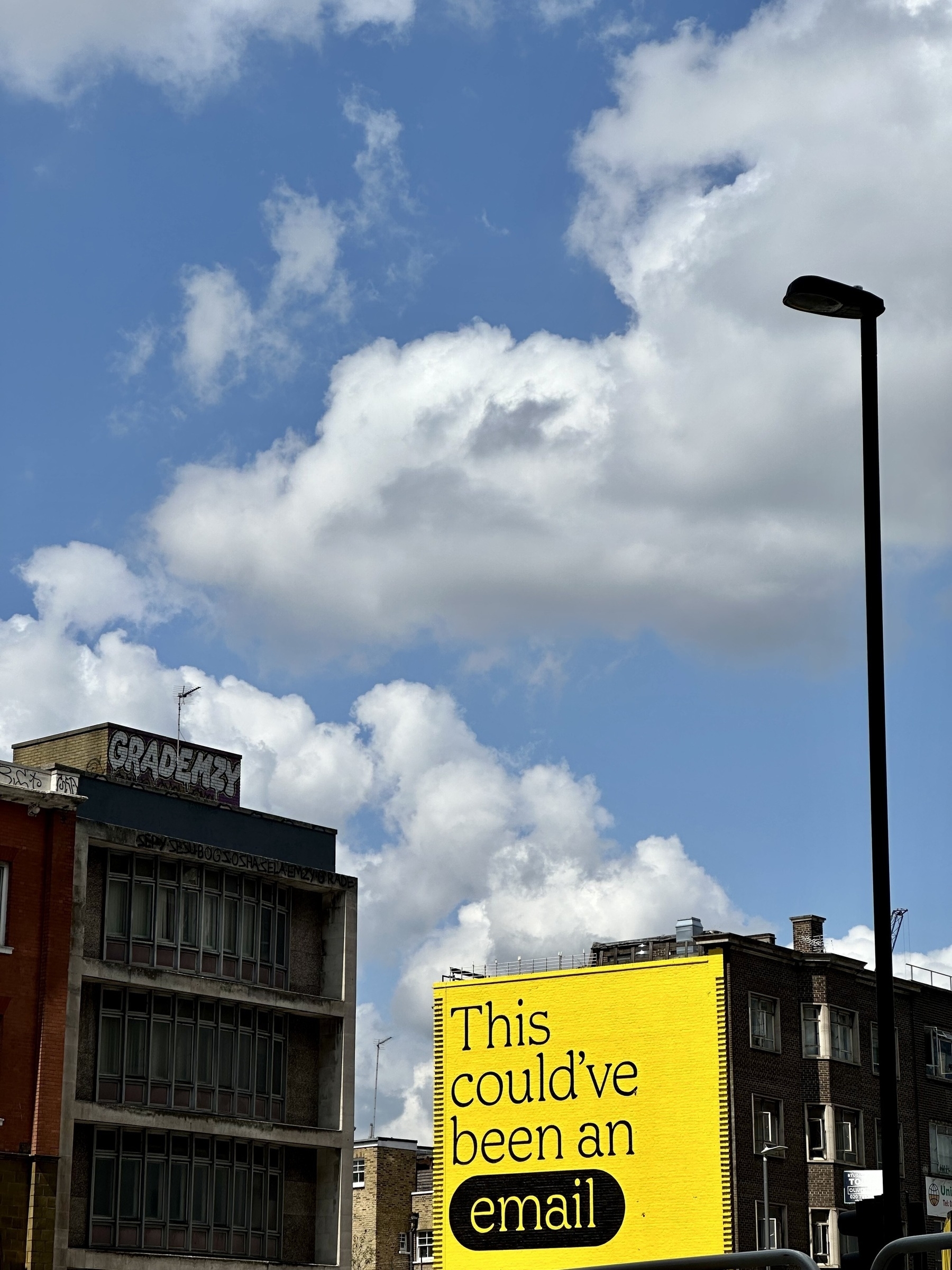 An advert on the side of a building saying “This could’ve been an email”, in black text on a bright yellow background.