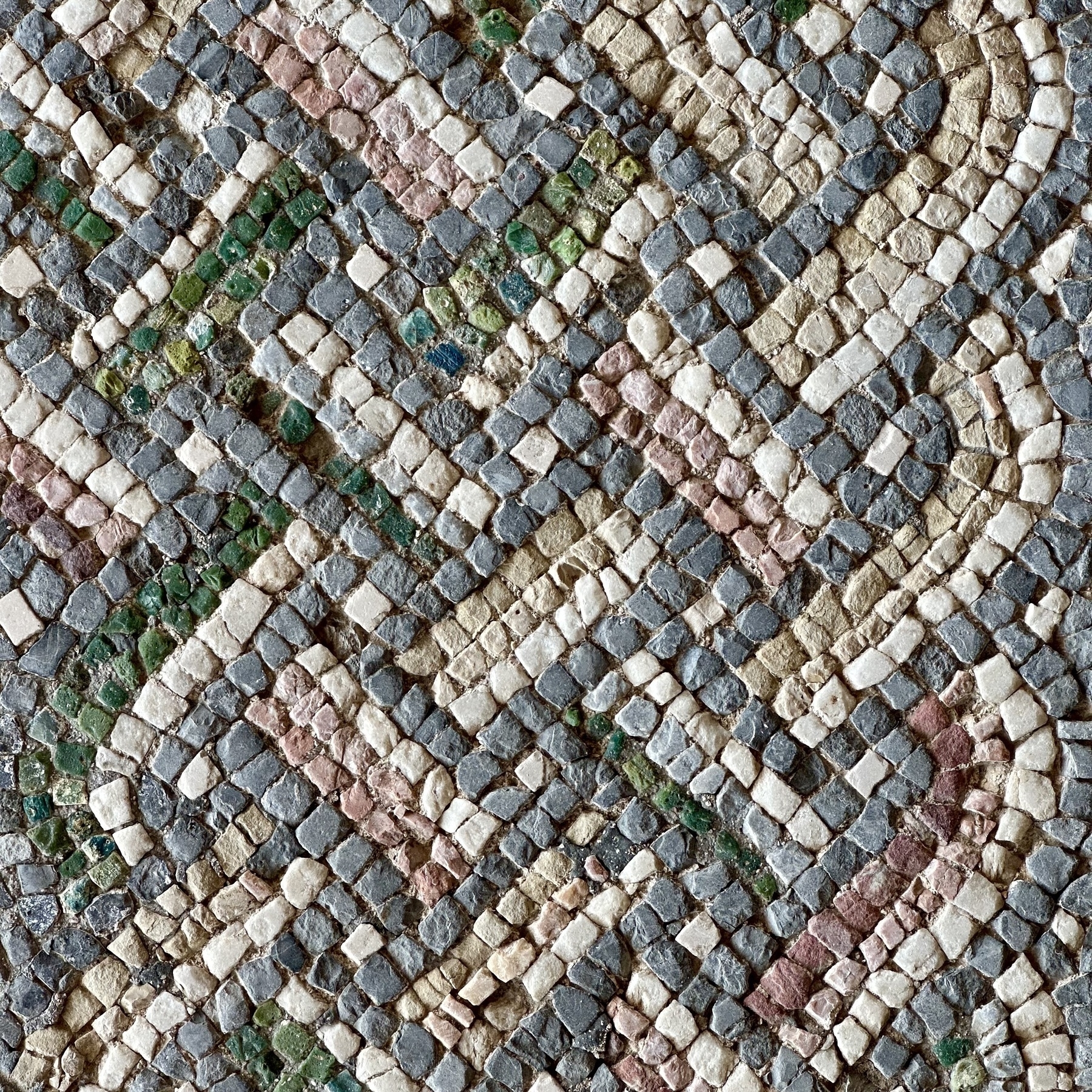 A geometric pattern mosaic of green, red, grey, and white tiles.