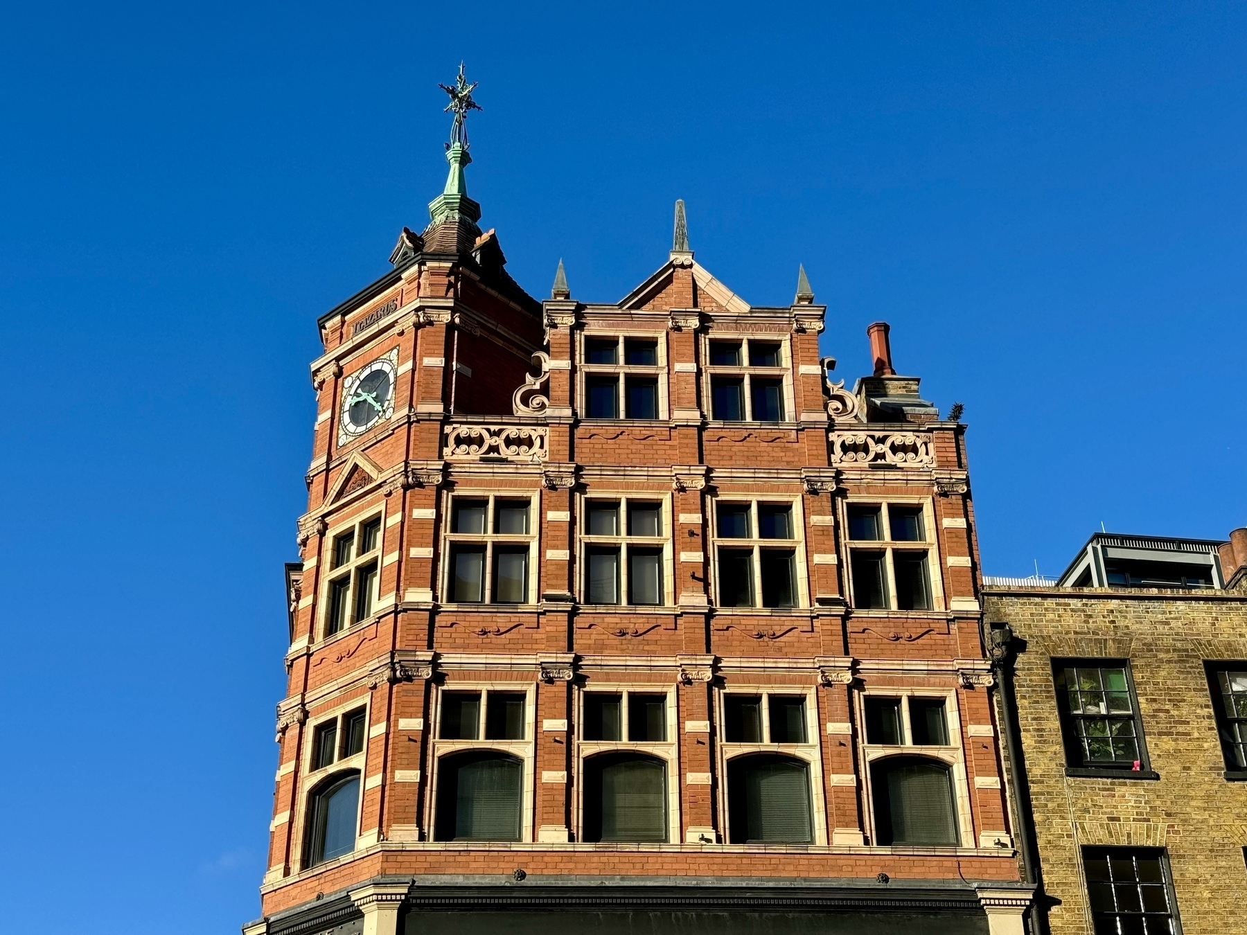 Red brick and sandstone building against a bright blue sky.