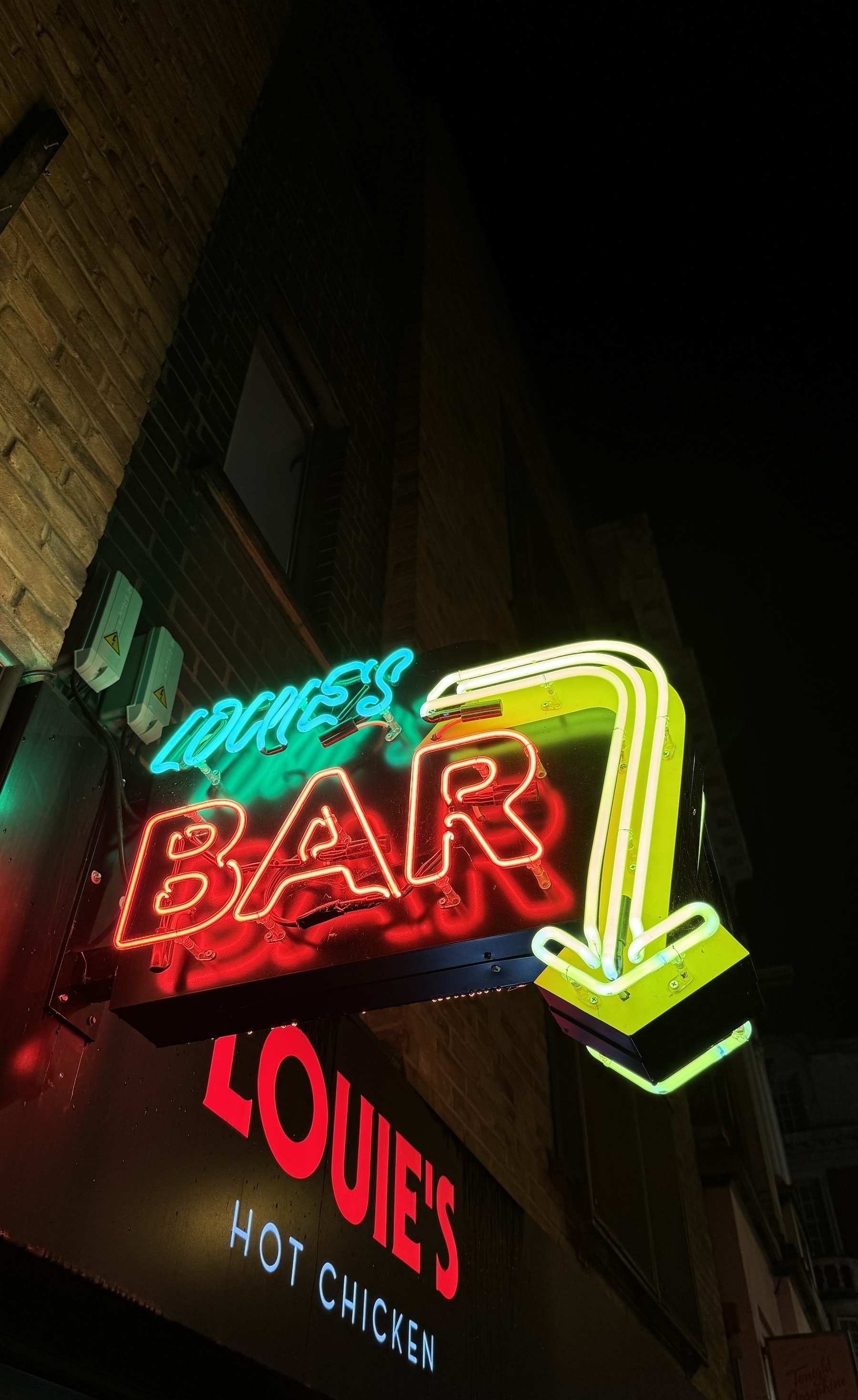 A neon sign that says Louie’s Bar.