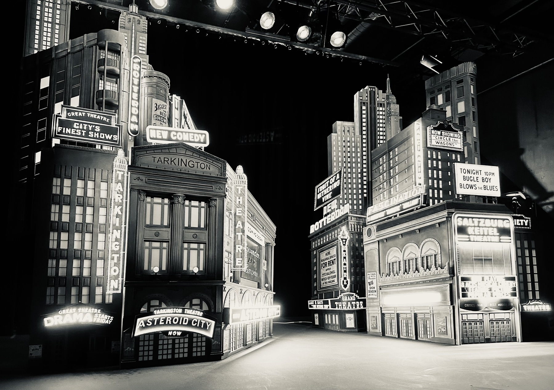 Black and white photo of a miniature film set of a theatre district, from the film Asteroid City
