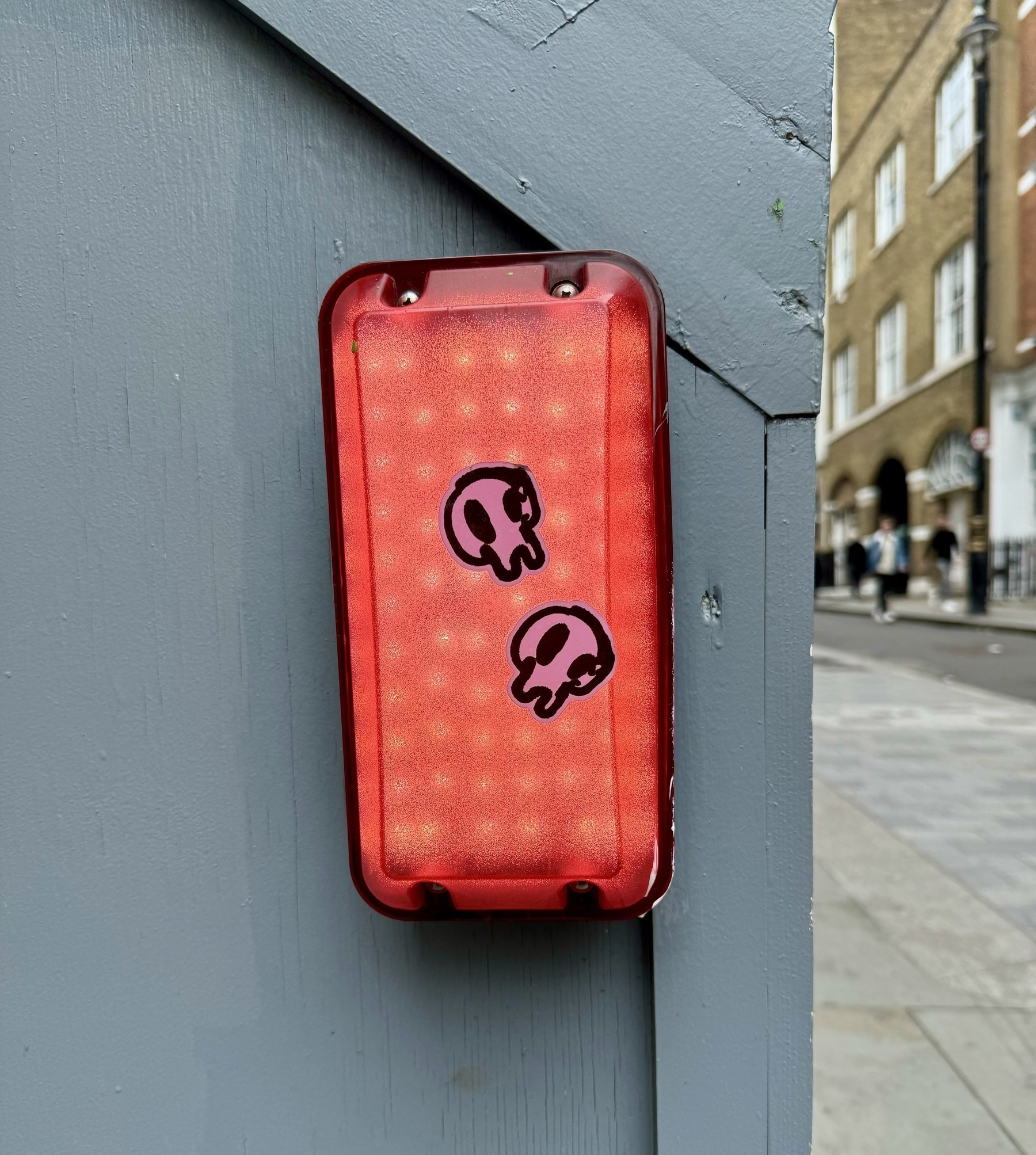 A red light attached to a grey wooden board, with two skull stickers on it.