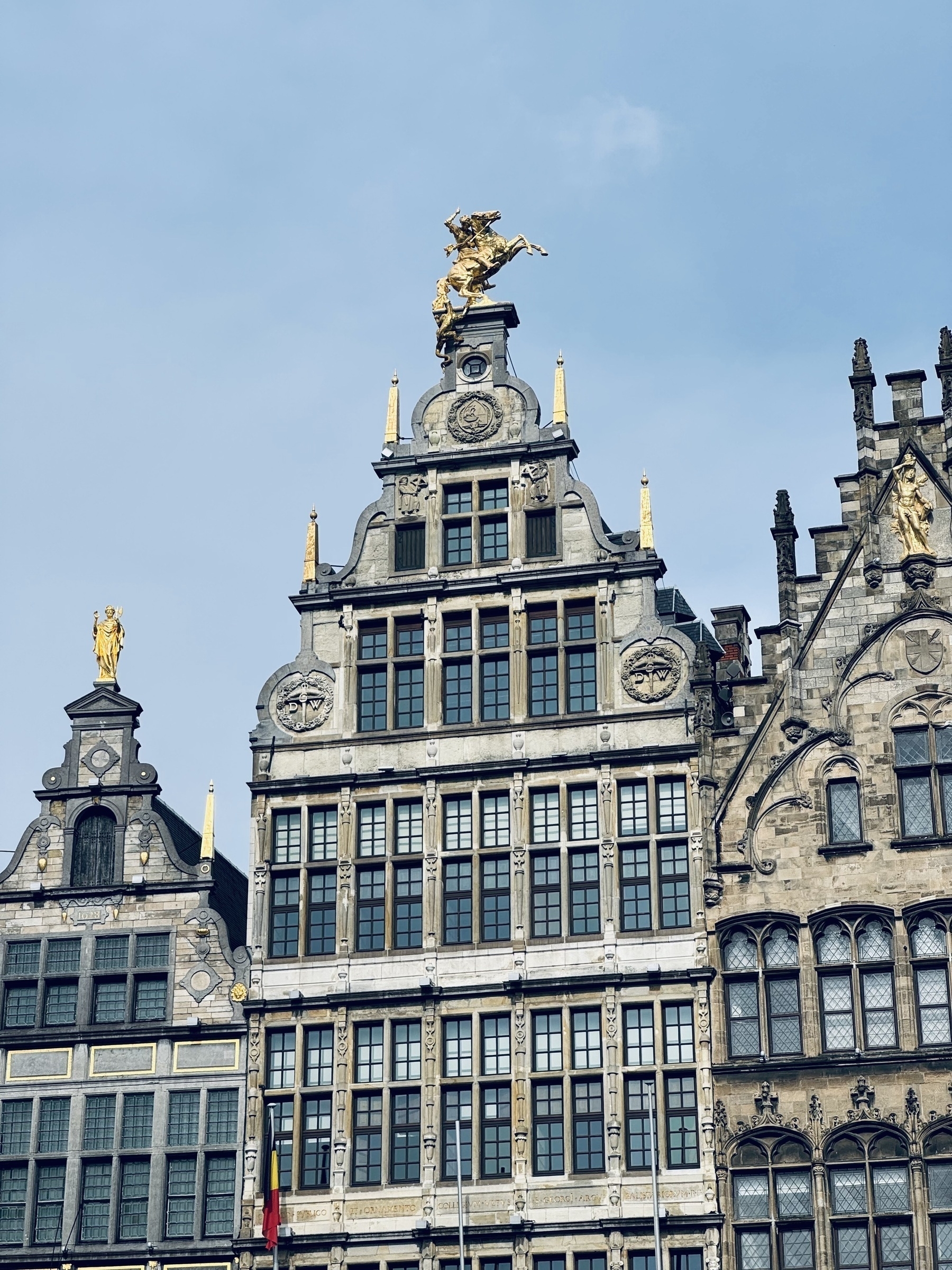 Shiny gold statues on the tops of buildings in the main square of Antwerp.