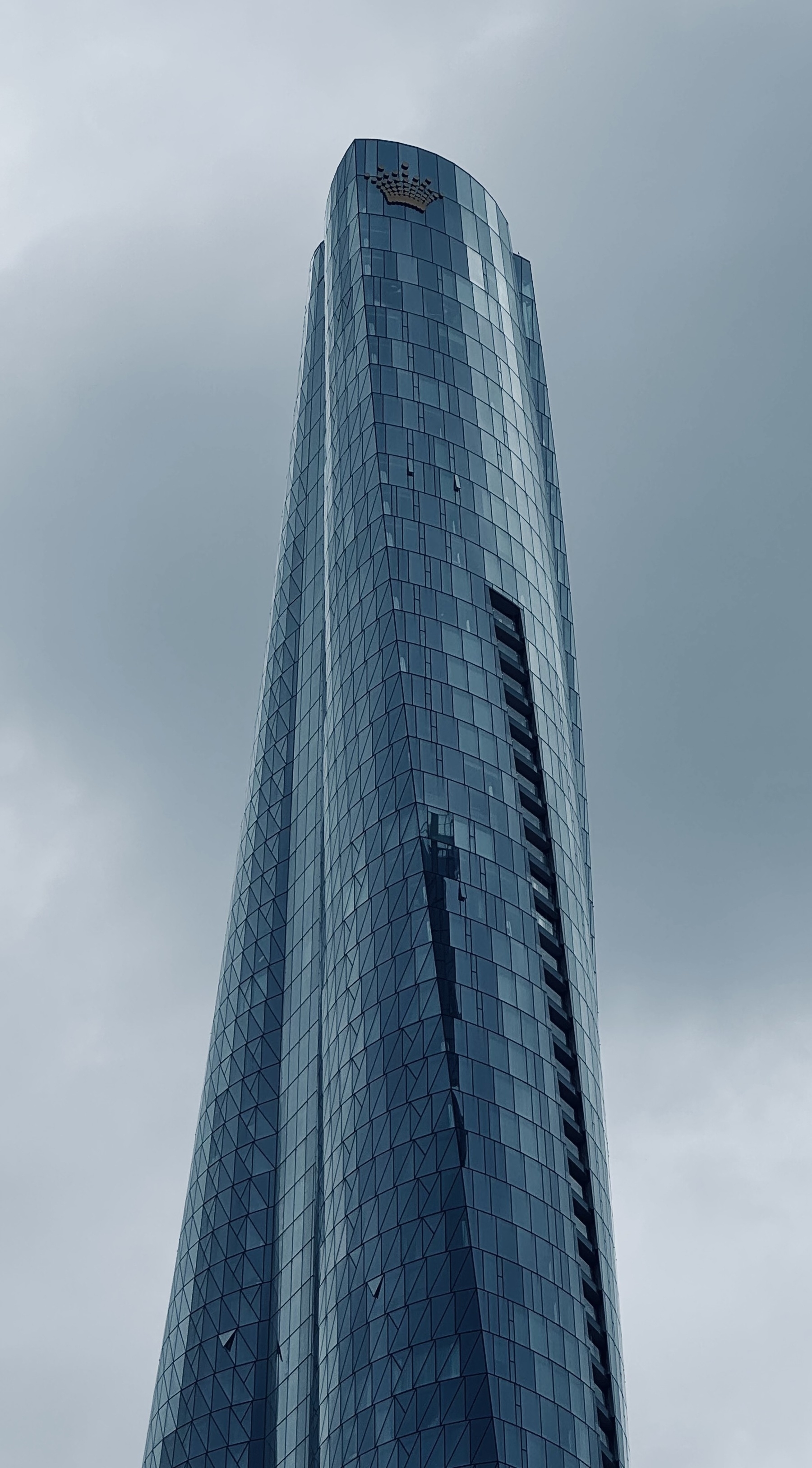A glass skyscraper with a twisted design against a cloudy sky.
