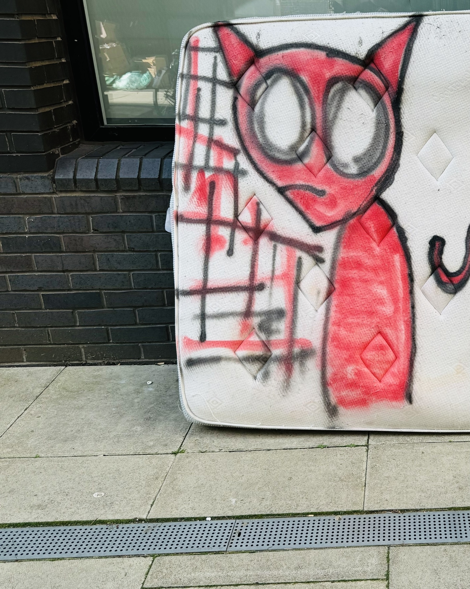 A devil spray painted on an abandoned mattress.