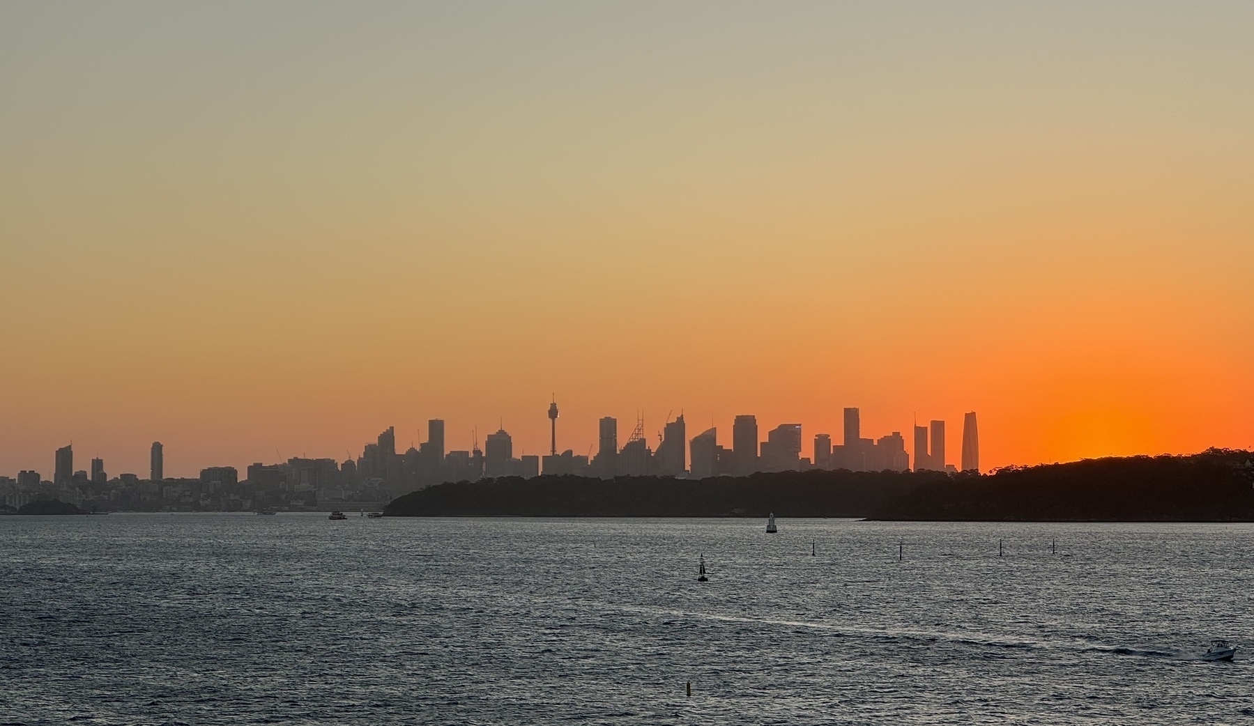The skyline of Sydney just after the sun has gone down. Slightly hazy with an orange sky.