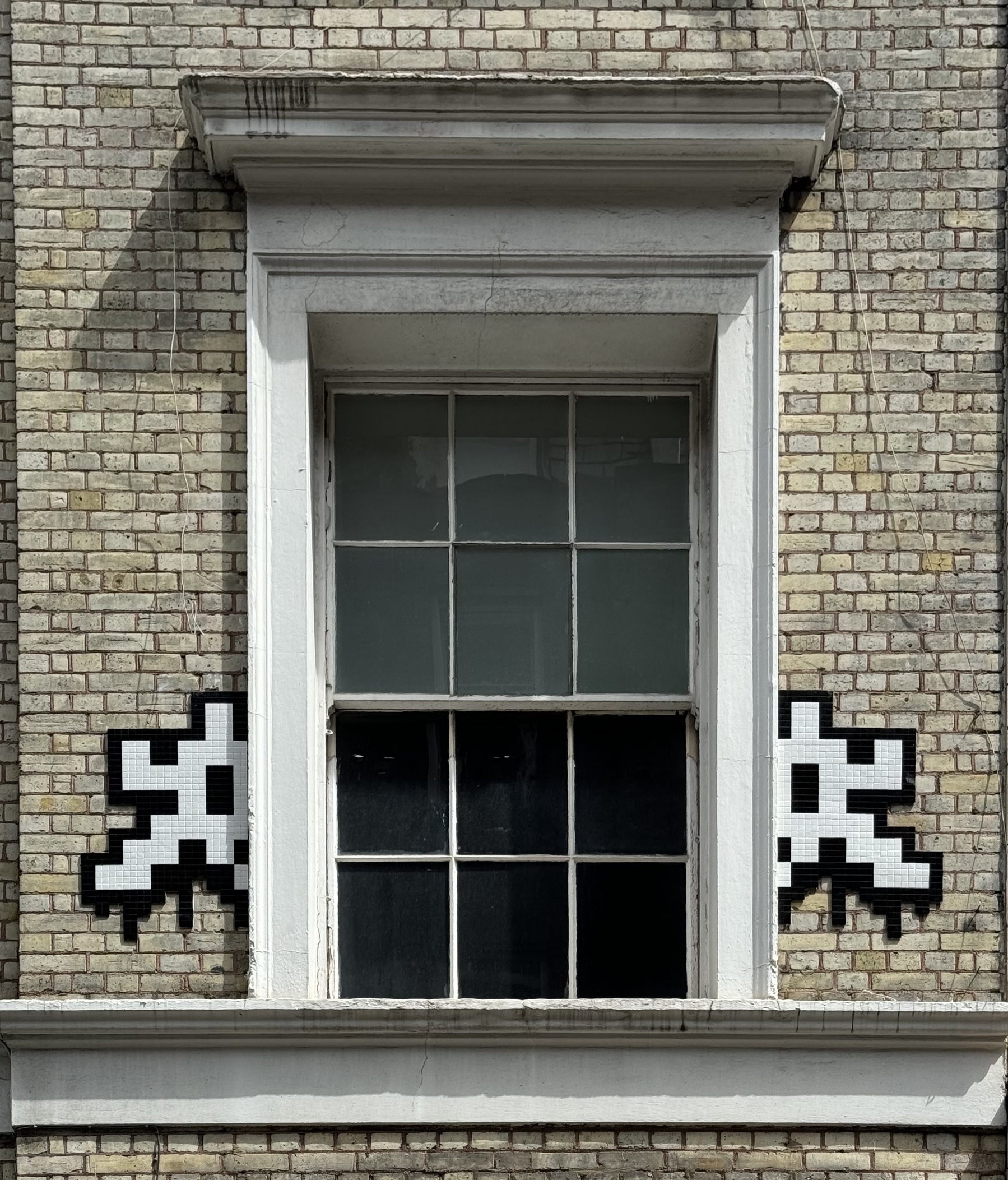 A pixelated space invader, split in half by a window.