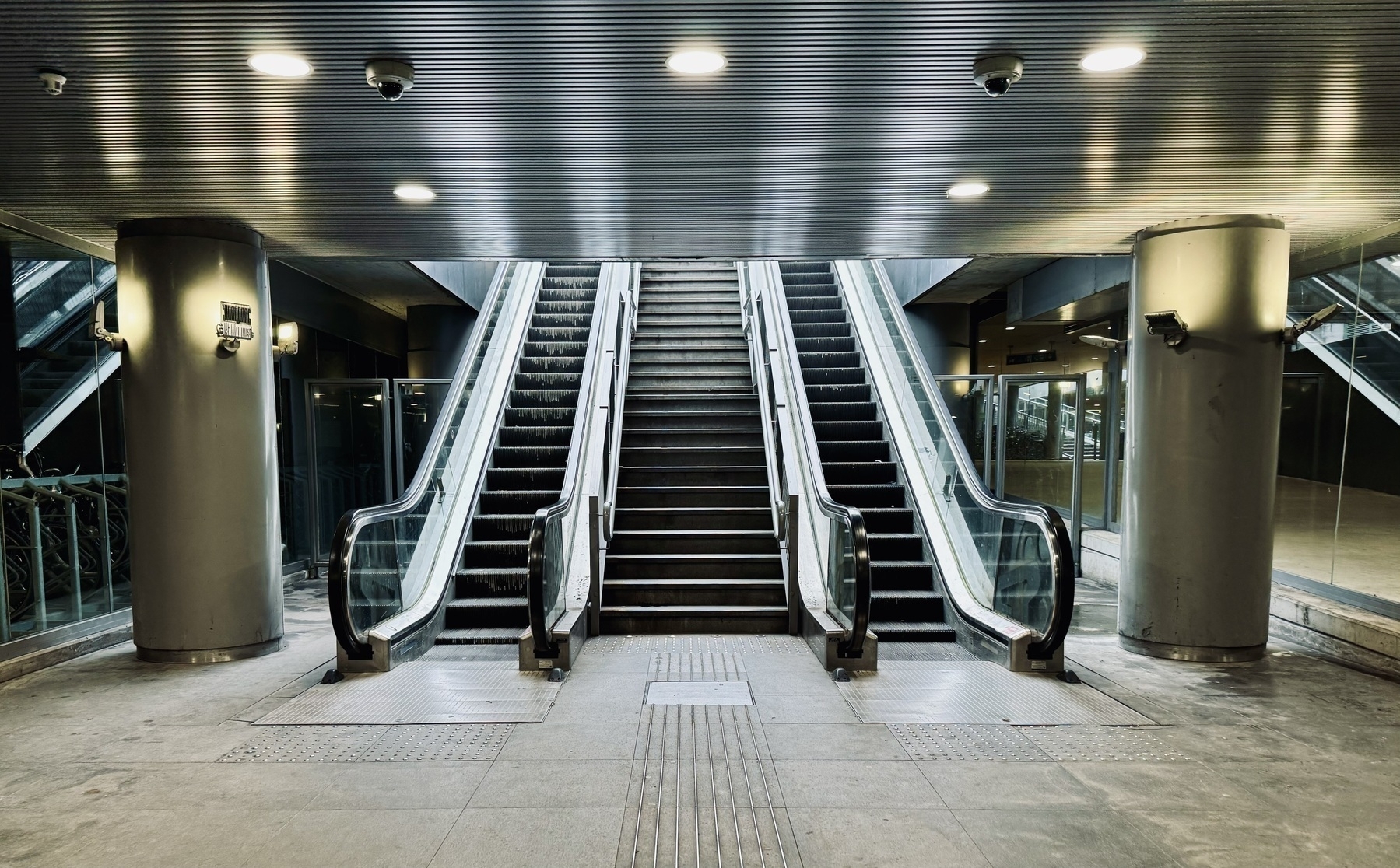 Two escalators flanking a staircase, going up in to the light.