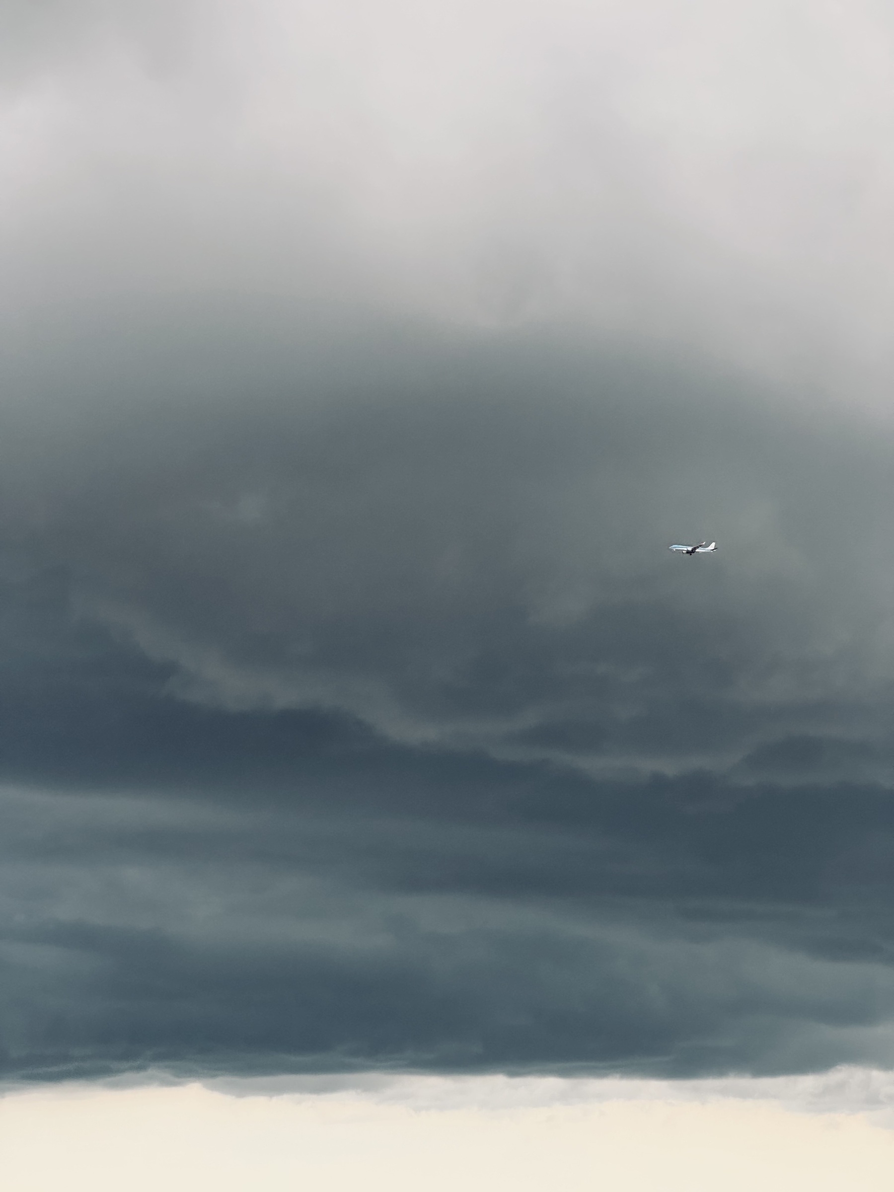 An airplane in the distance with a dark cloud behind it.