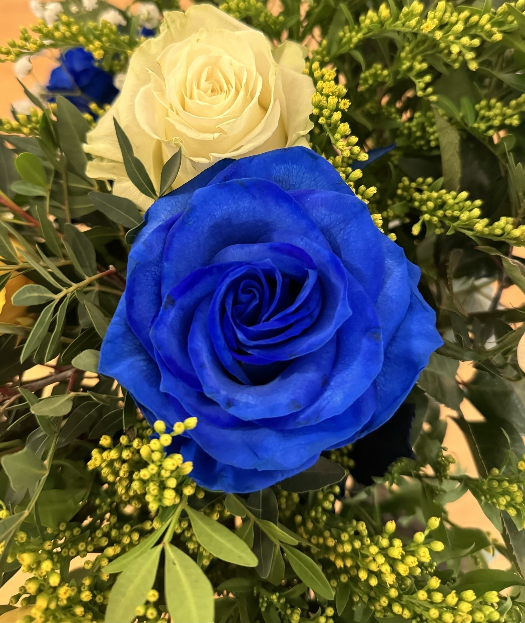 A blue rose in a bouquet of flowers.