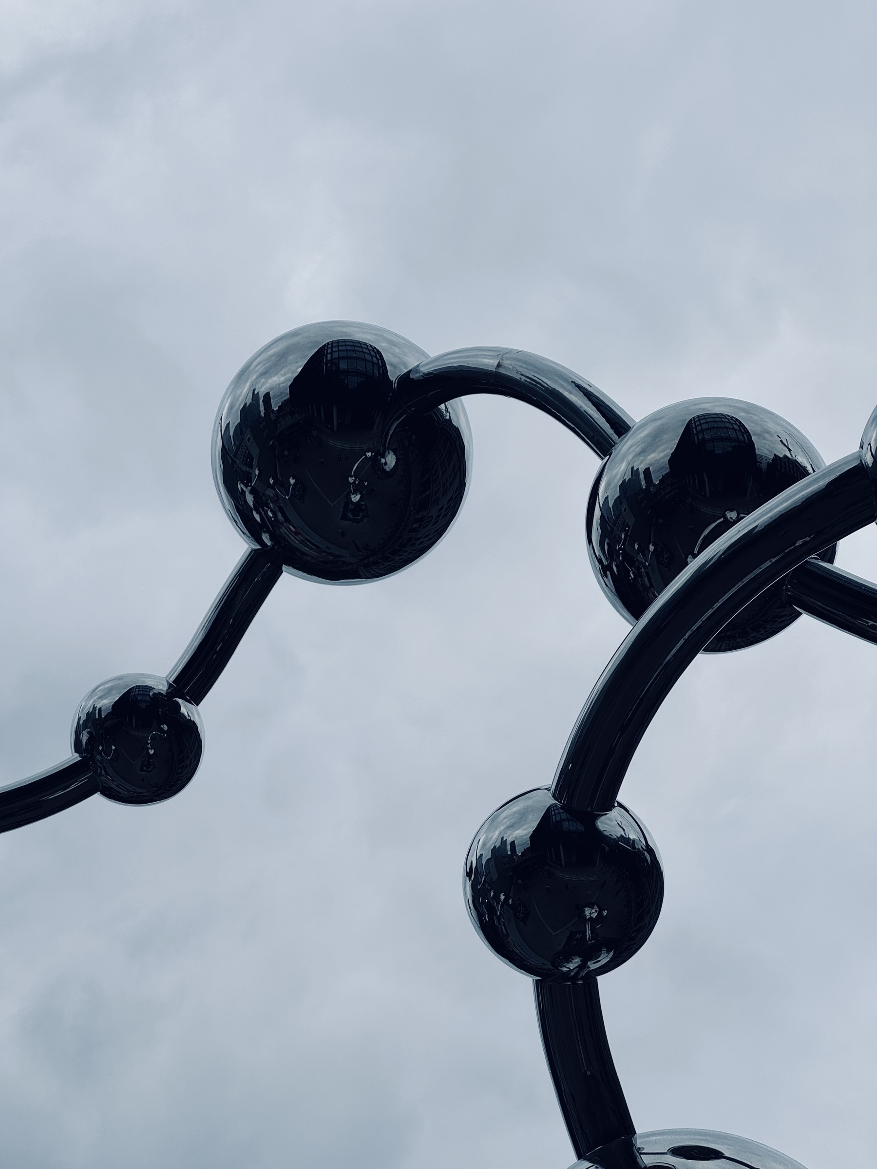 A shiny metal sculpture of balls on twisty supports.