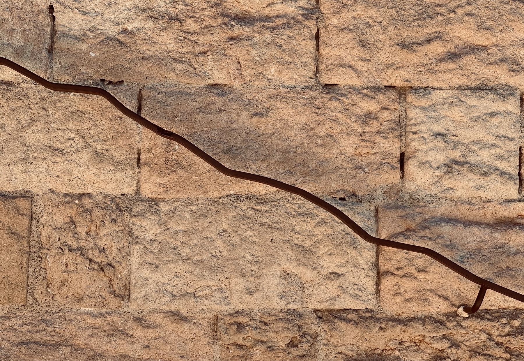 A wiggly metal handrail going down a stone wall.
