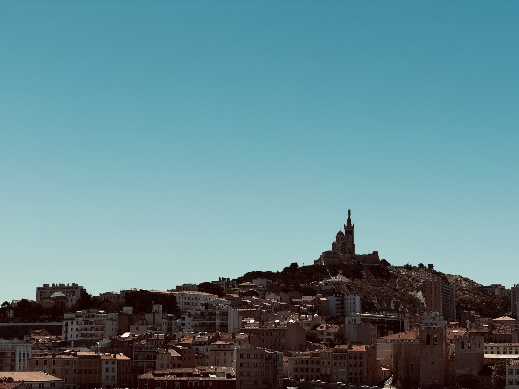 A church perched on the top of a hill under a clear sky, looking down on the city below.