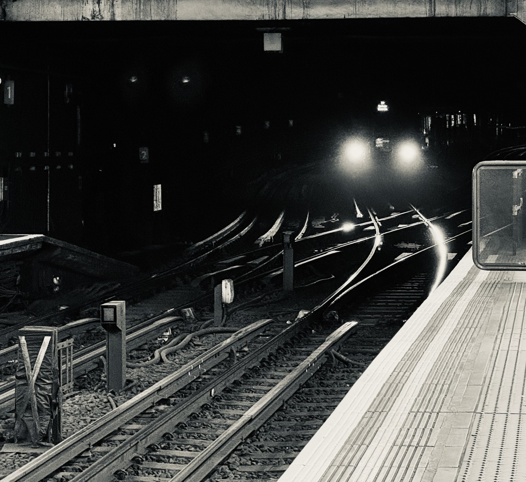 A tube train about to emerge from the darkness in to Aldgate East station.