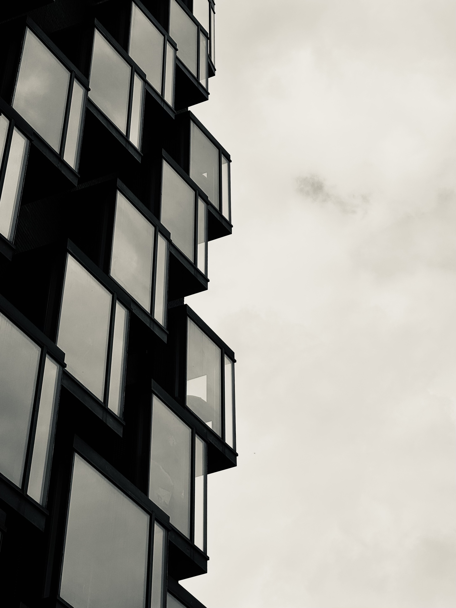 Boxy windows sticking out from a building against a cloudy sky.