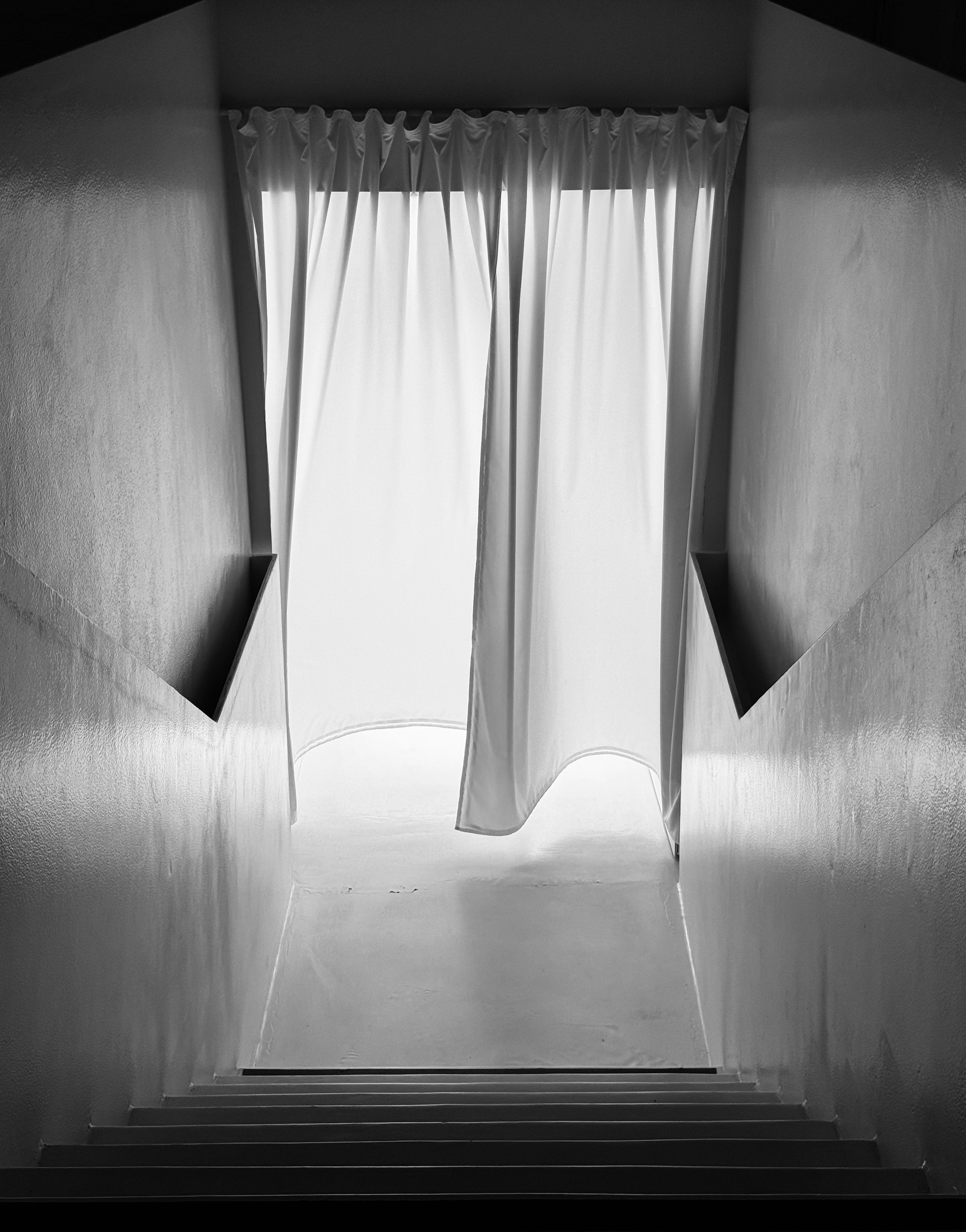 Stairs leading down to a brightly backlit translucent curtain.