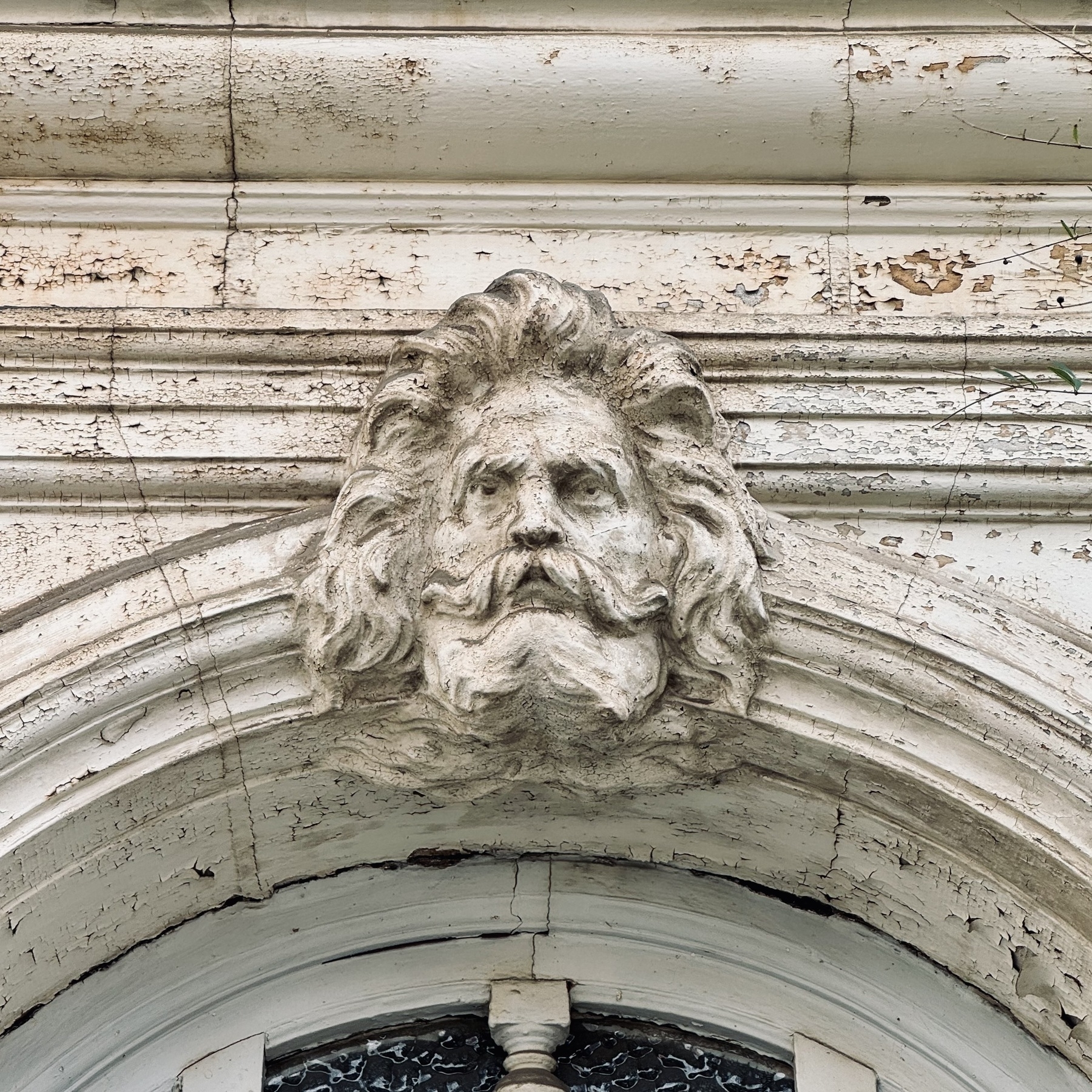 A carved bearded face with a mane of hair above a door.