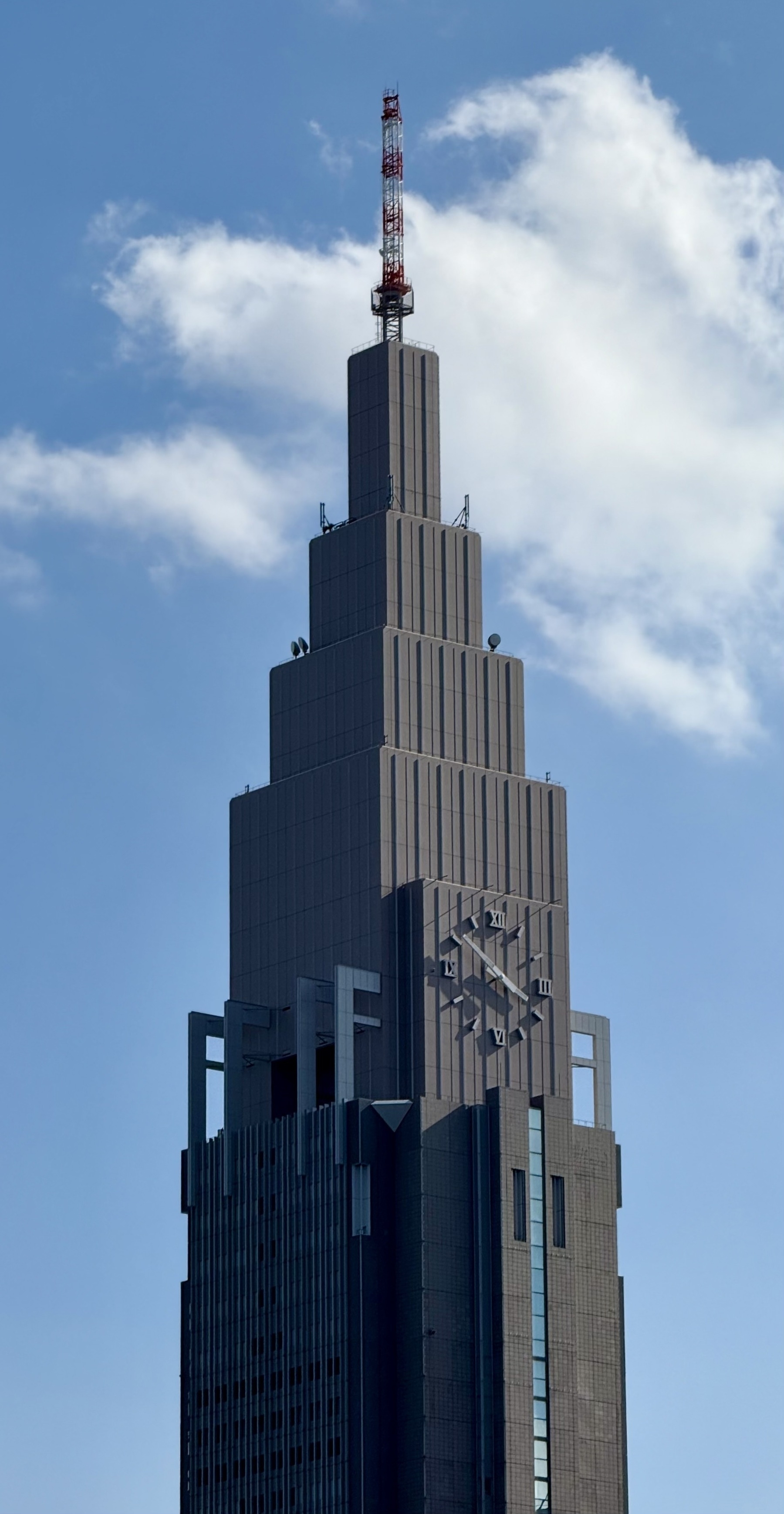 A concrete skyscraper with a clock on it.