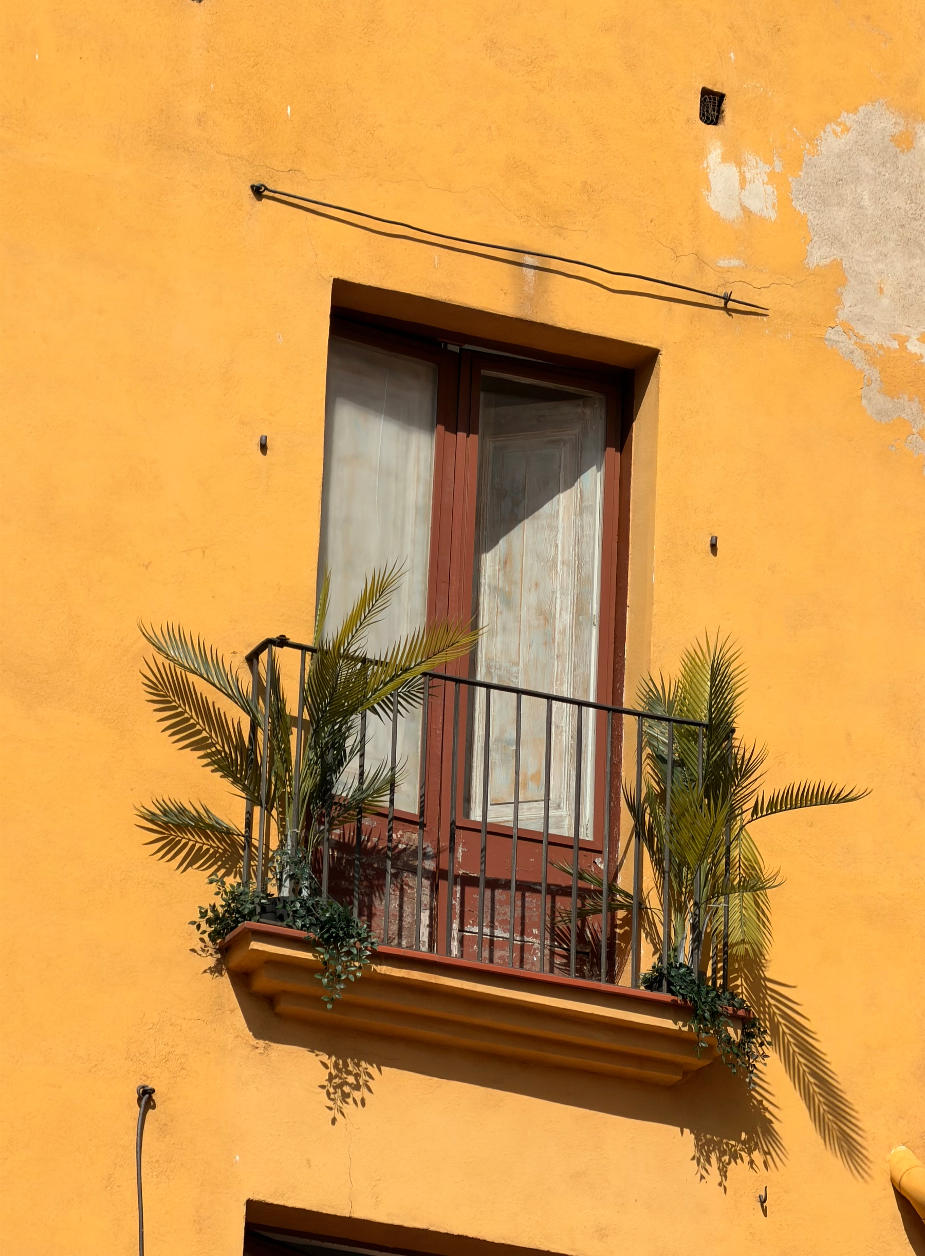 A window with balcony in a yellow building.