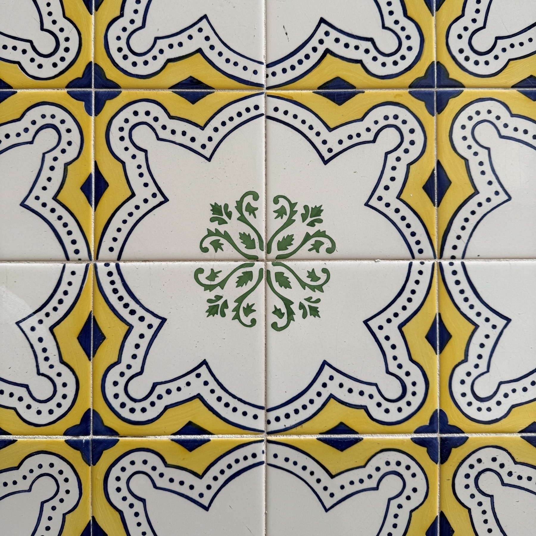 Blue and yellow tiles with a green floral pattern in the middle.