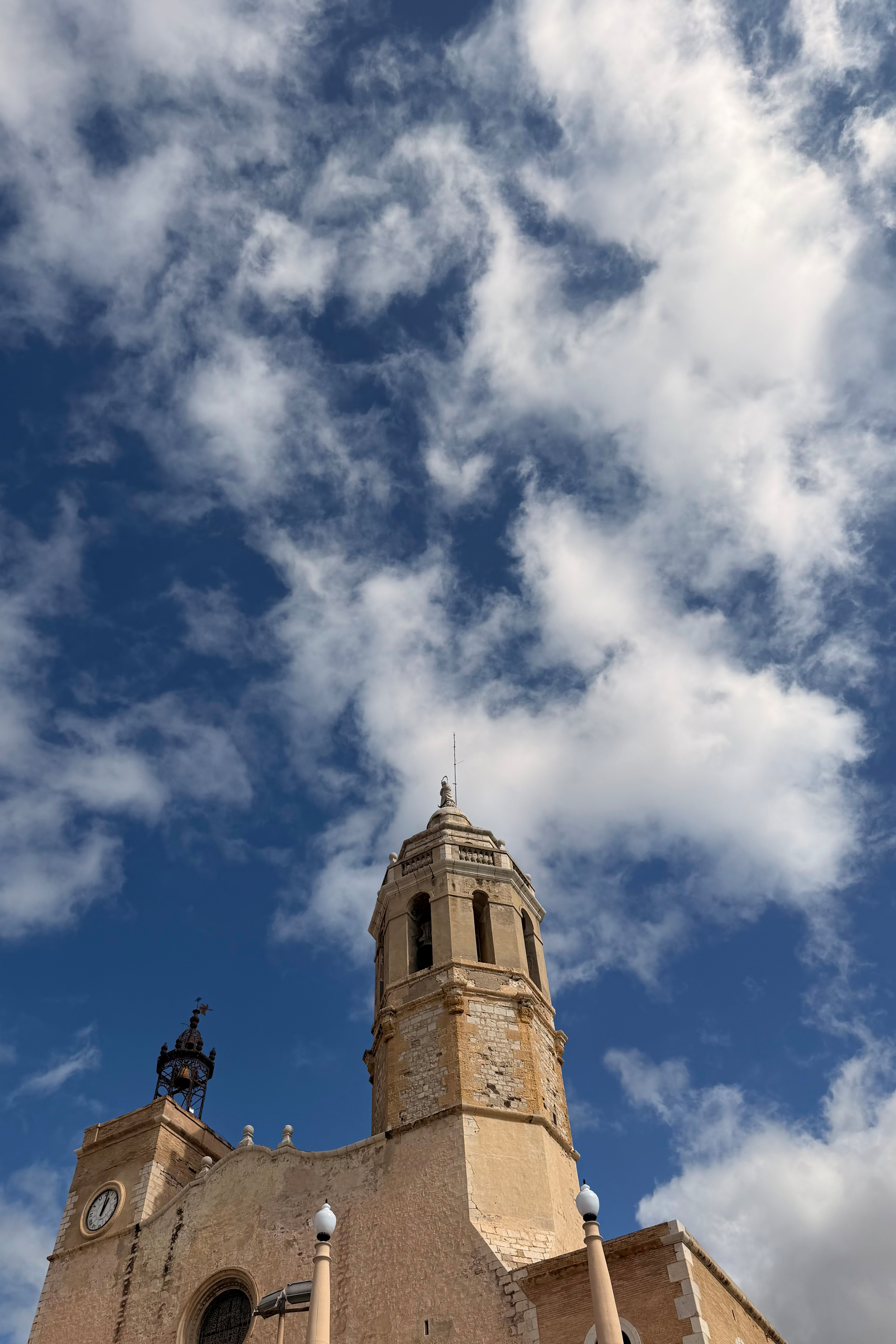 Looking up at a church tower with a cloudy sky behind.