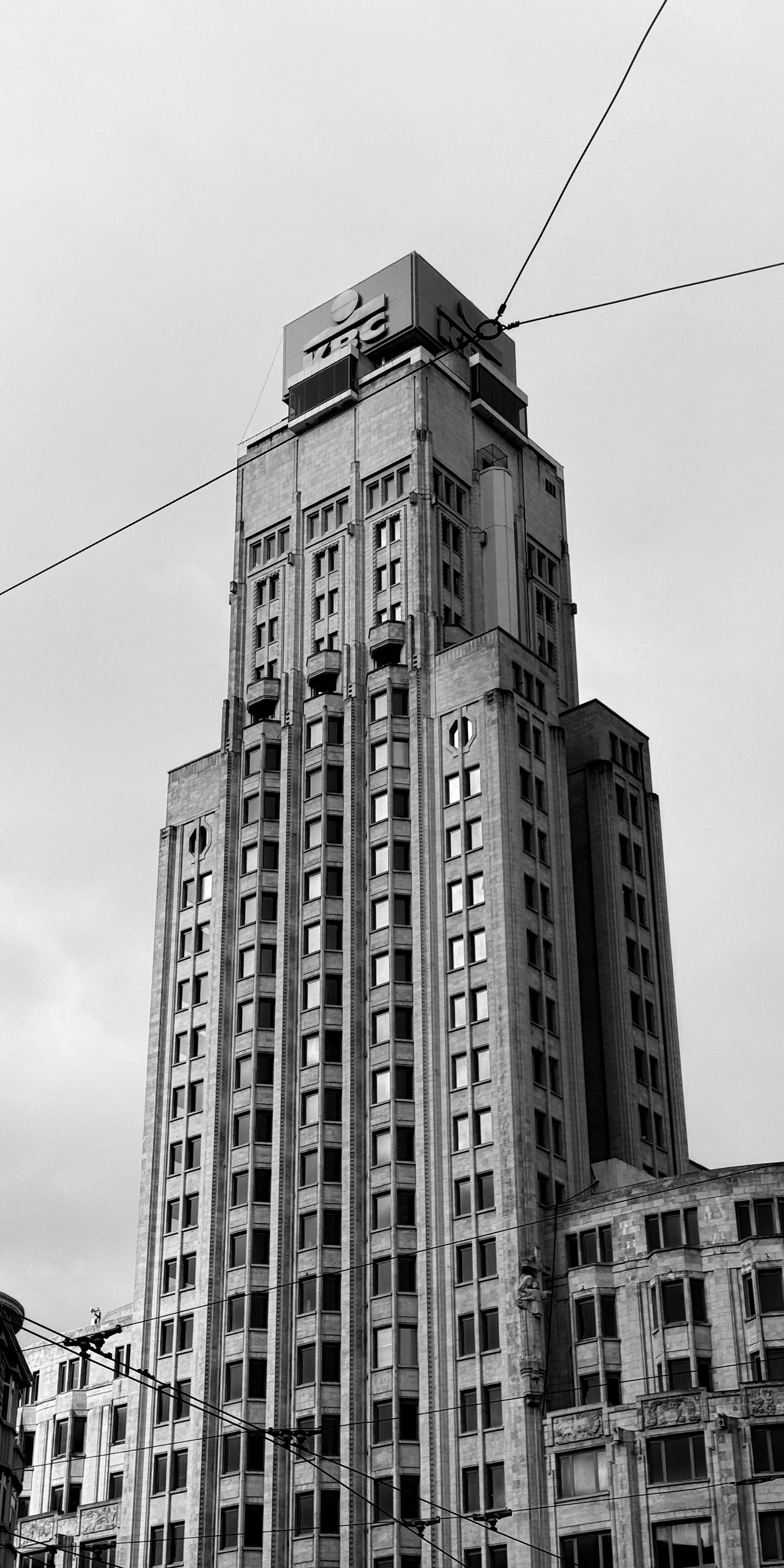 Black and white photo of a tall stone tower block against a white sky.