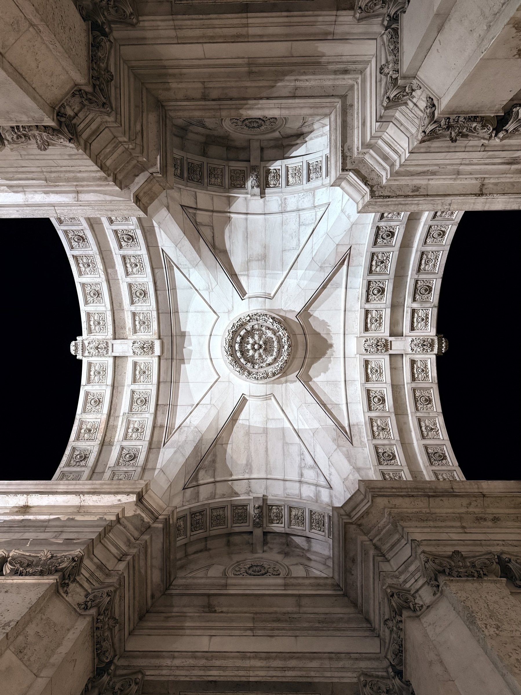 Looking straight up at the ornate stone Rua Augusta arch in Lisbon.