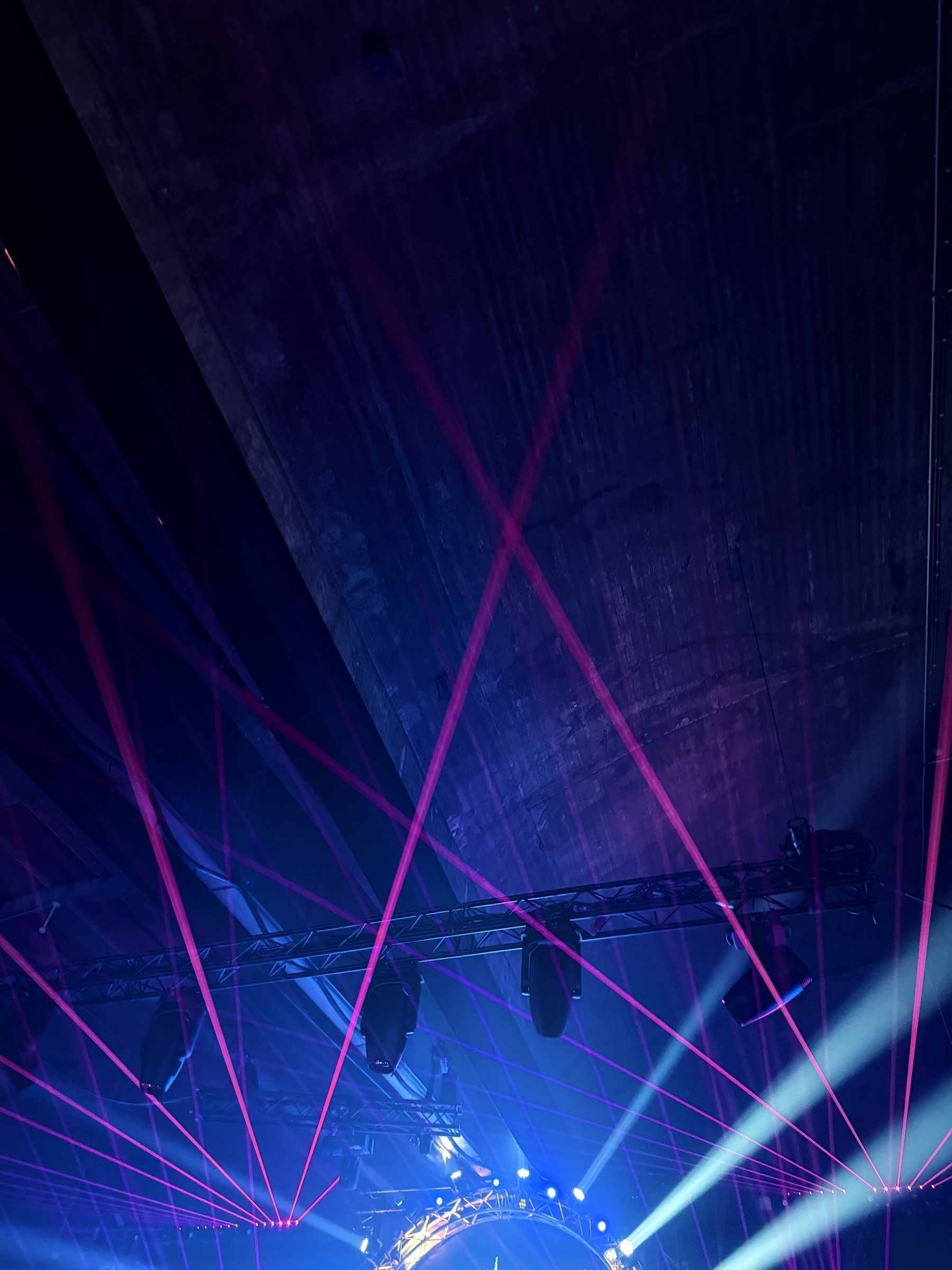 Red lasers shining out beneath the ceiling of a warehouse.