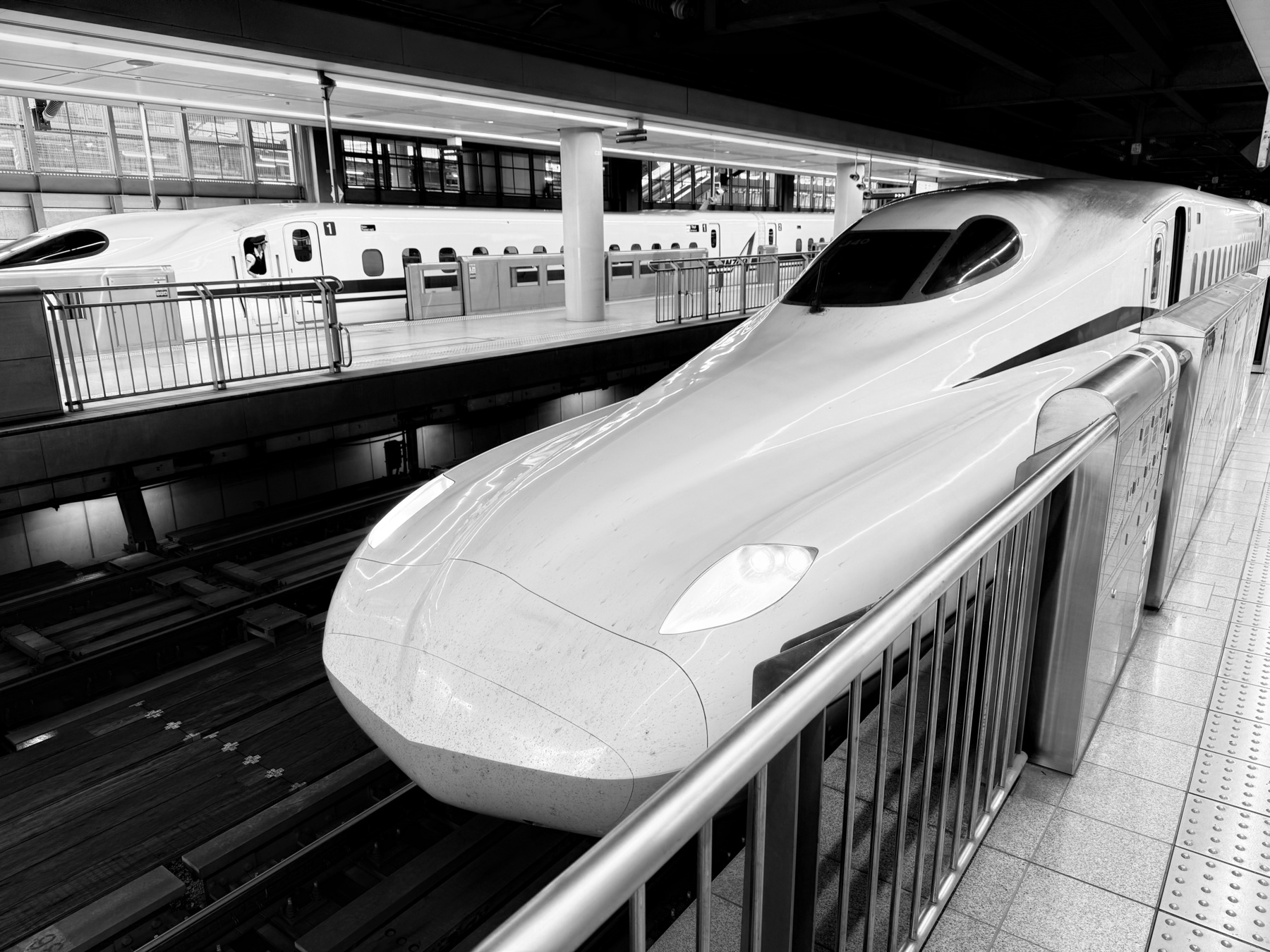 Black and white photo of the front of a bullet train in Tokyo Station.