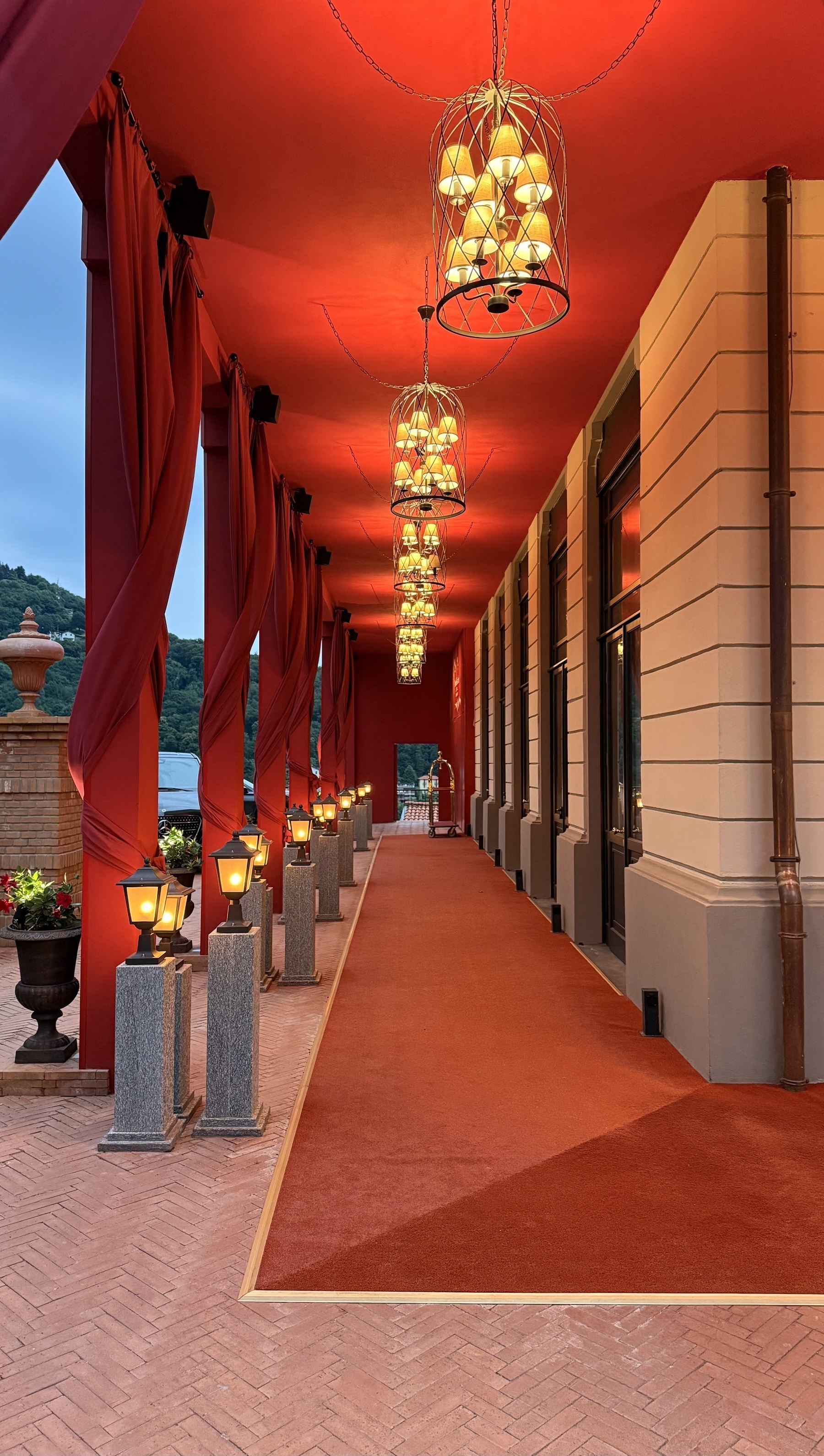 An outdoor walkway at the side of a hotel with red carpet, red ceiling, and red drapes.