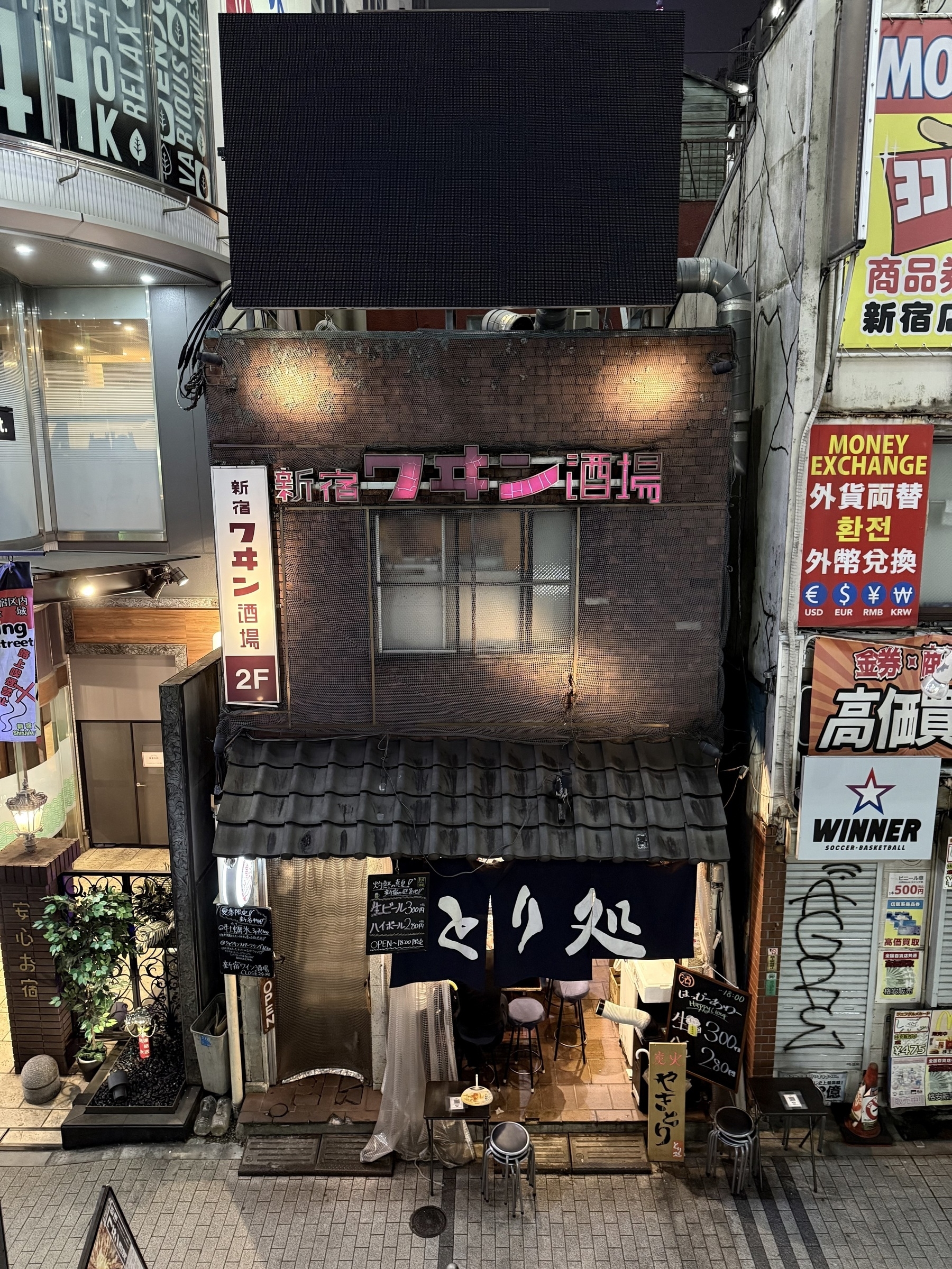 A small two storey brick building between two taller buildings in Tokyo.