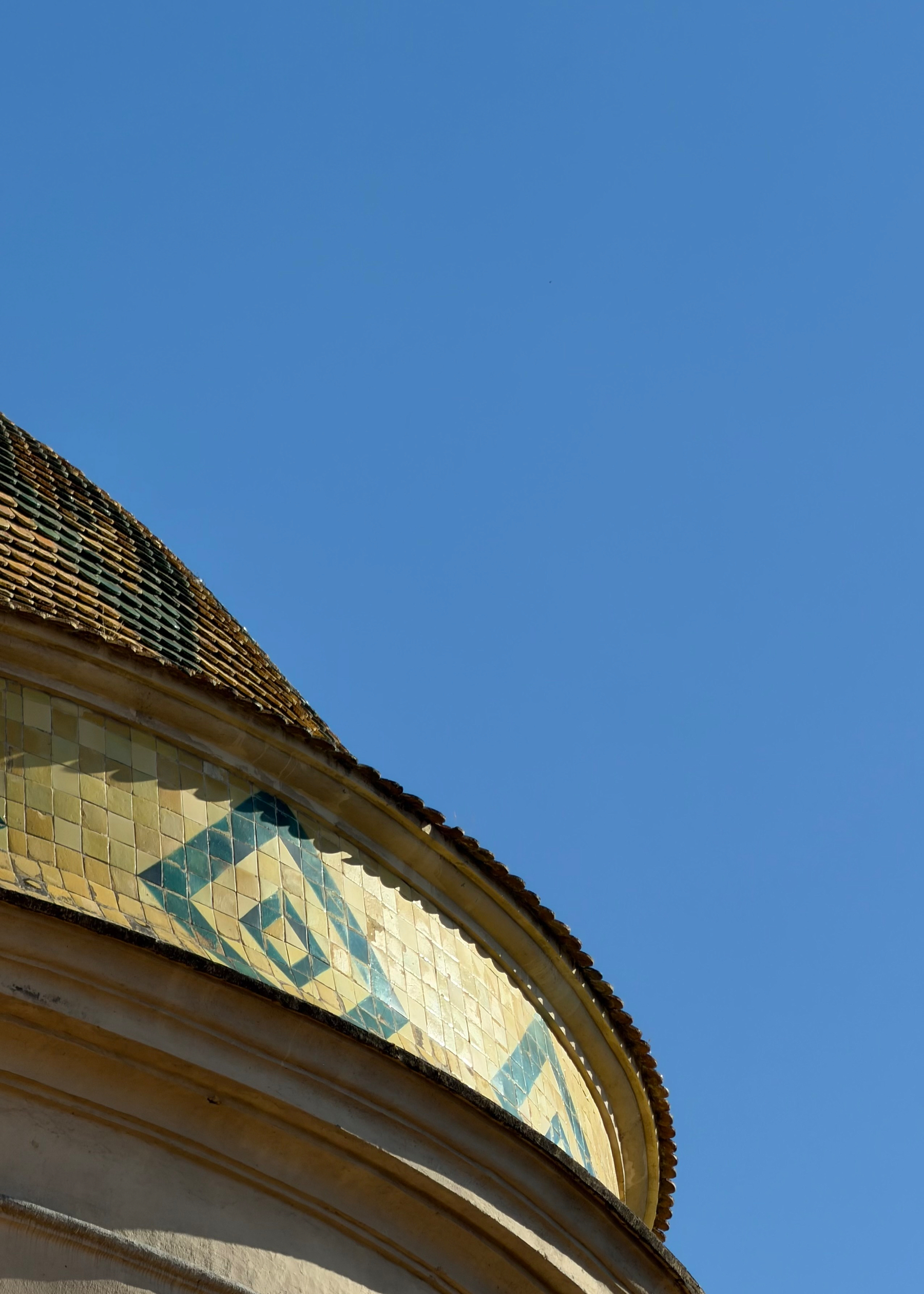 A curved tiled roof against a blue sky.