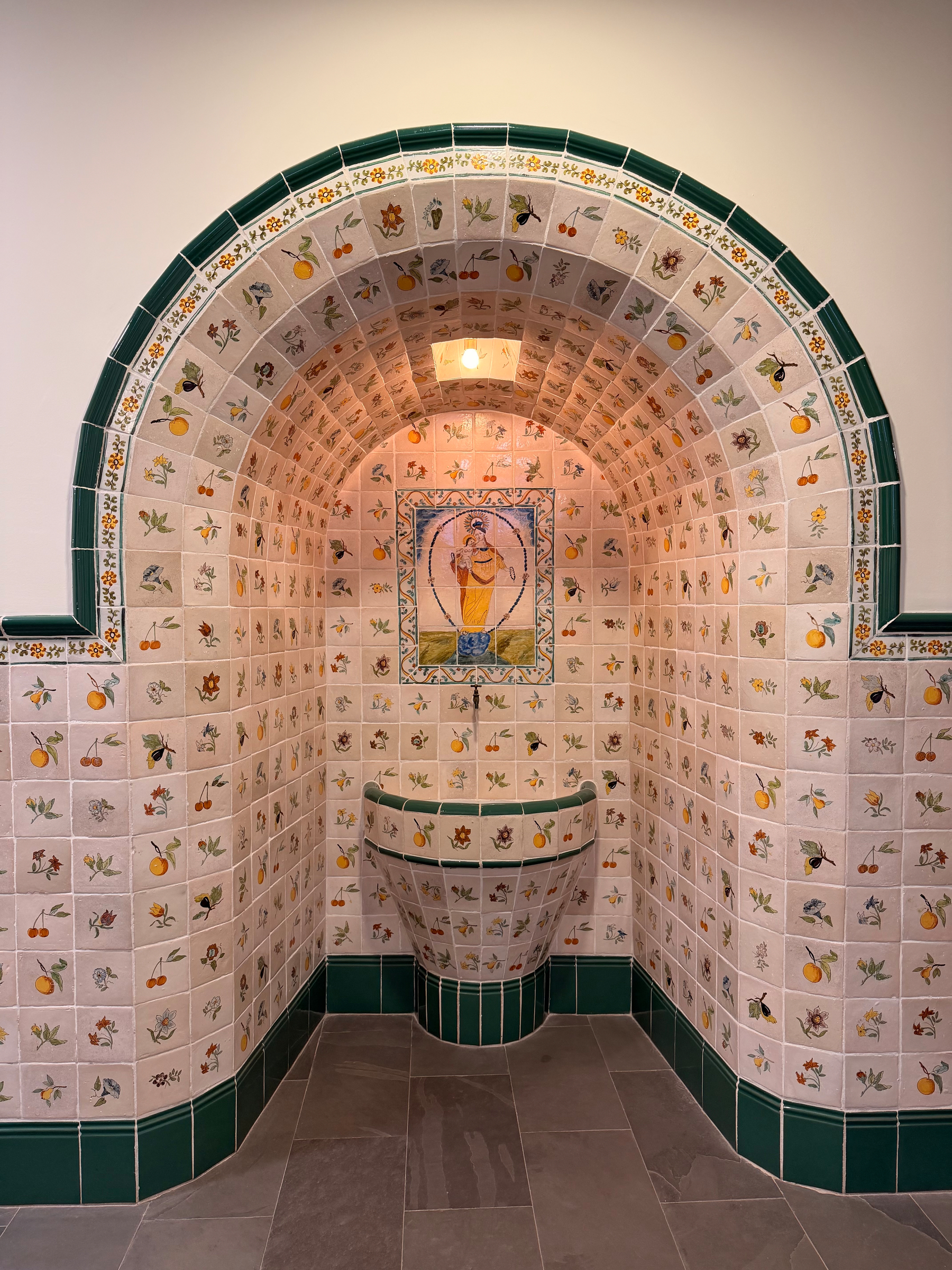 An ornately tiled font in an alcove.