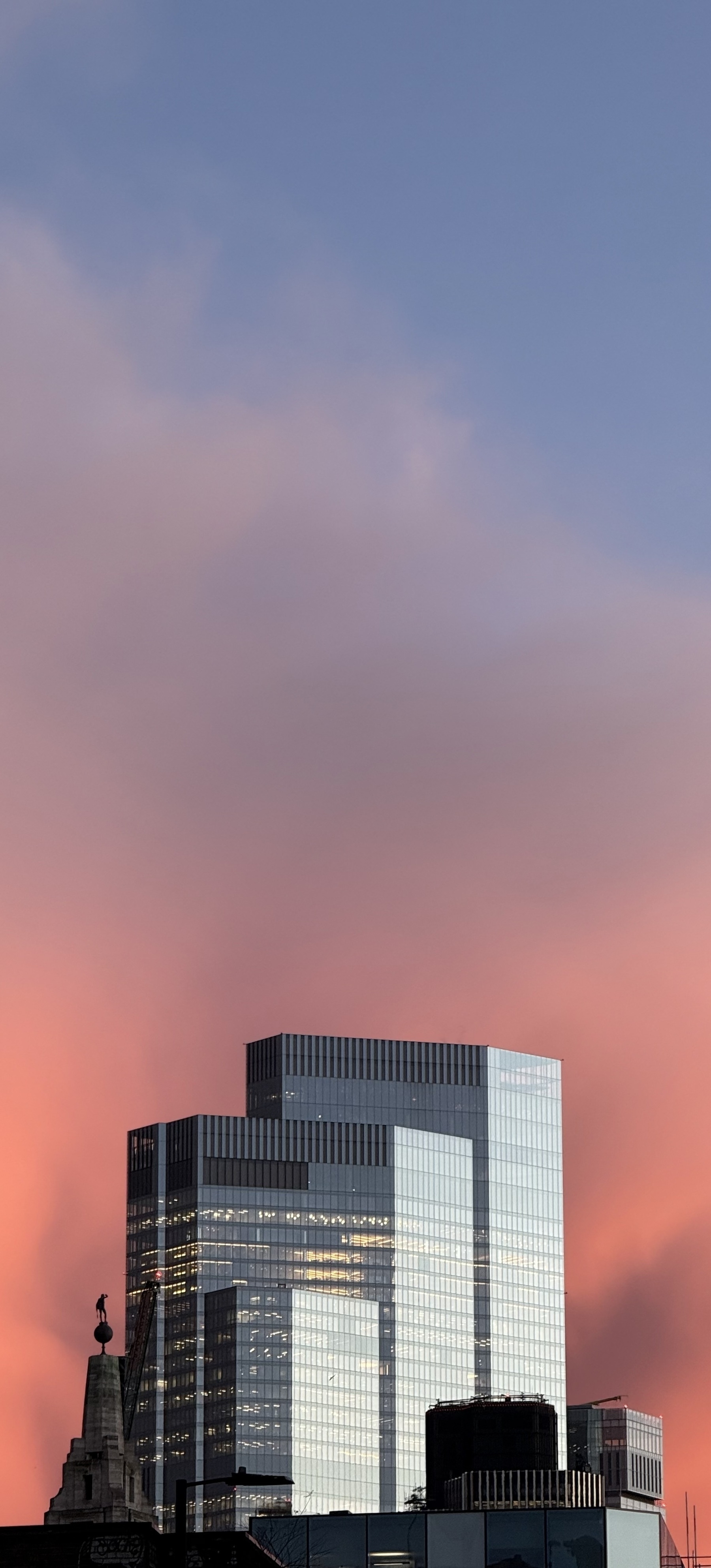 Glass skyscrapers against a pink sky at sunset.